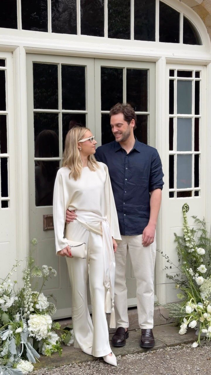 Woman in a white coordinated two-piece set and man in blue shirt standing together.