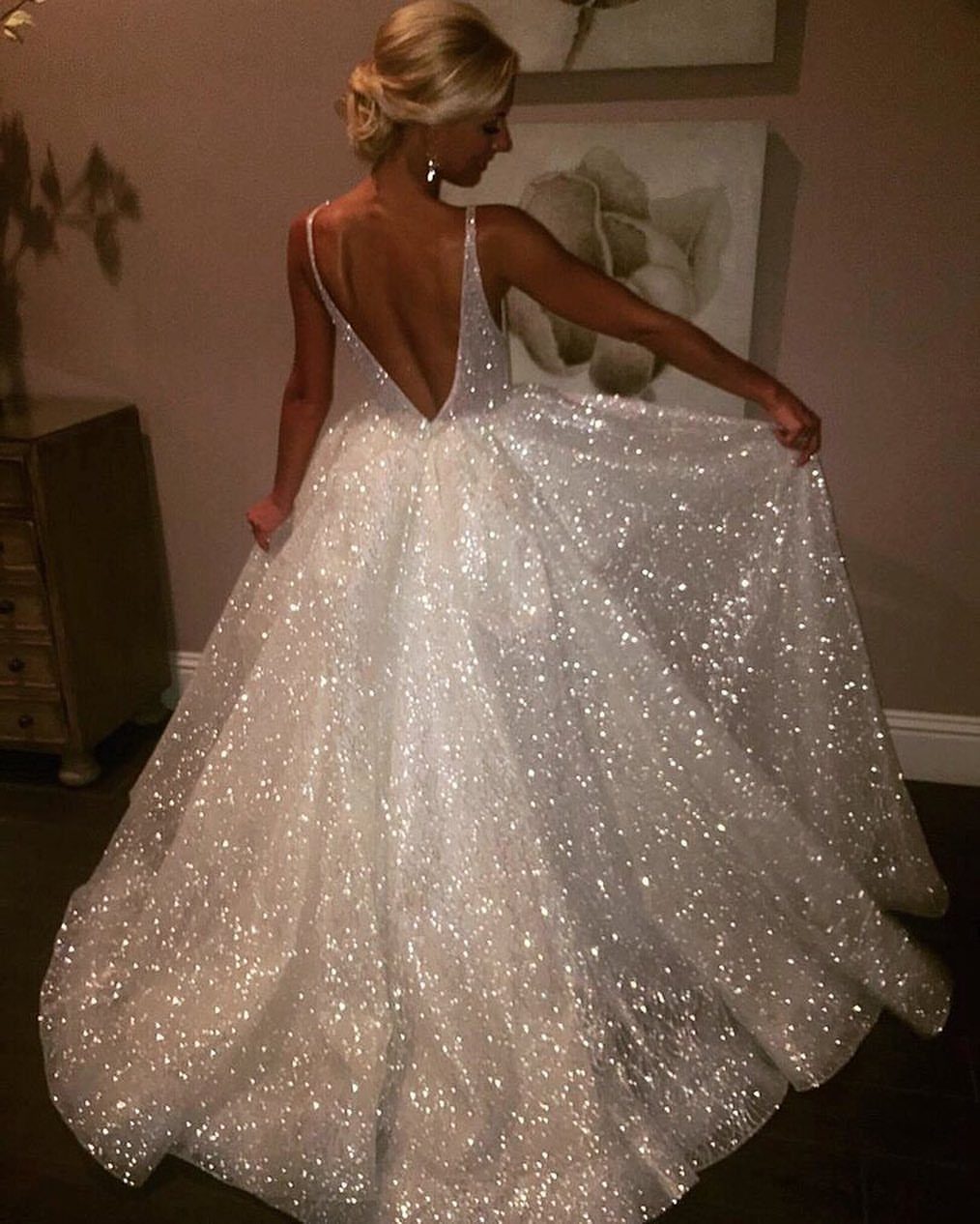 Woman in a sparkling white sequin gown with a deep V-back and full skirt.