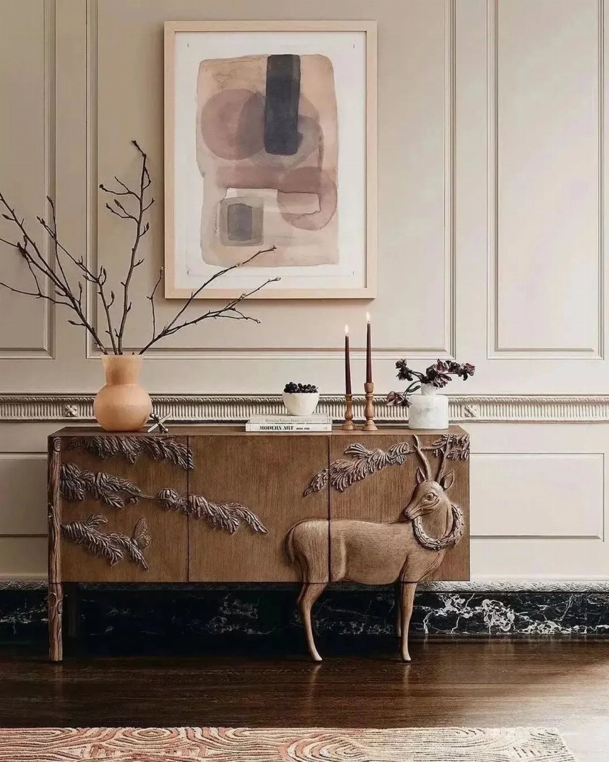 Wooden sideboard with carved antelope and branches against a paneled wall