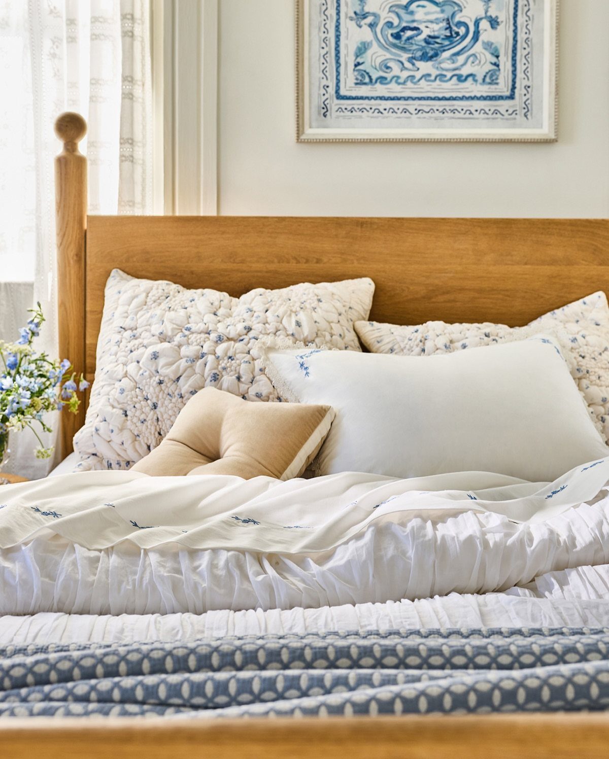 Wooden bed with white and blue patterned bedding and framed wall art