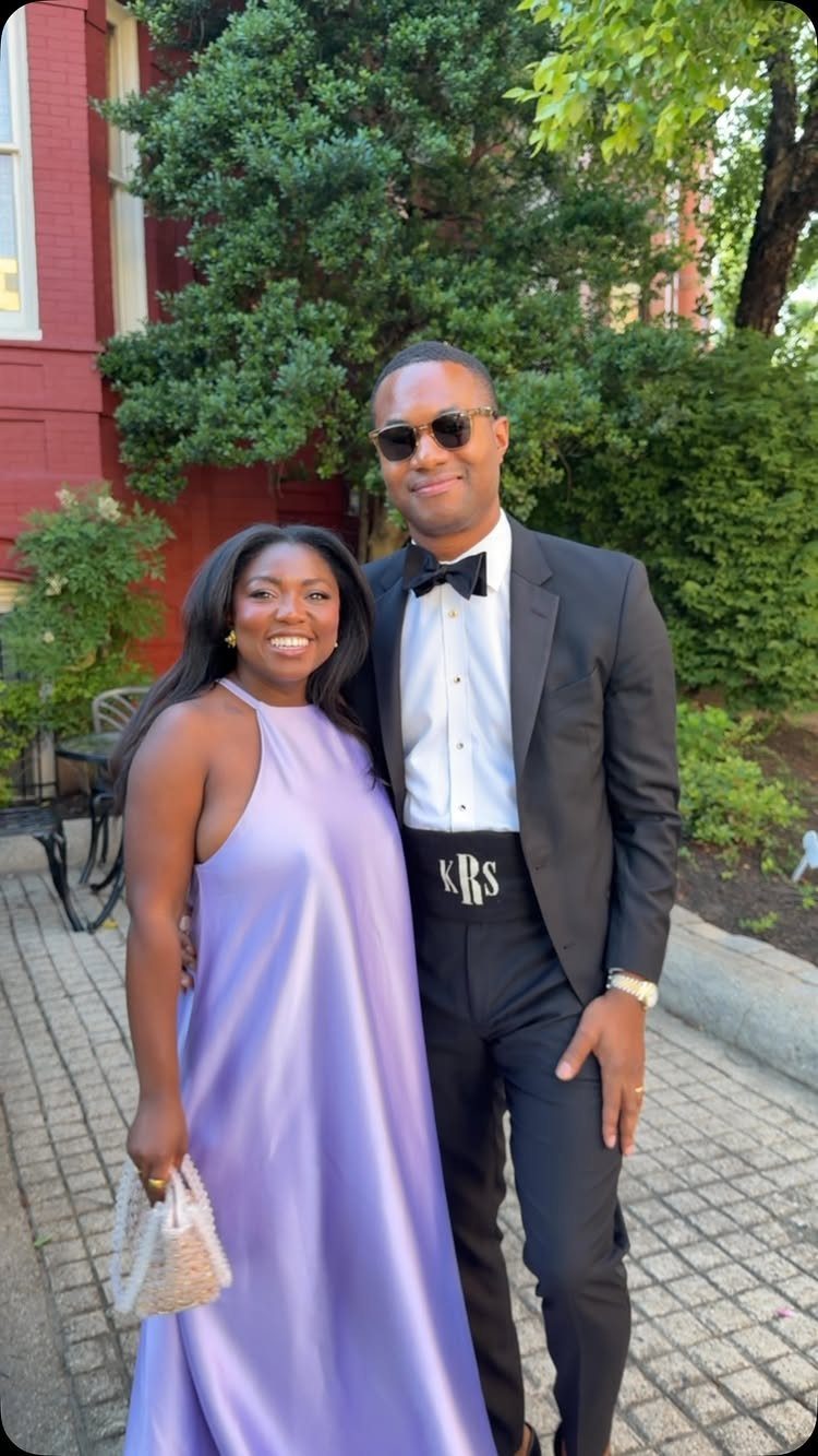 Couple in formal attire, woman in purple satin gown and man in black tuxedo.