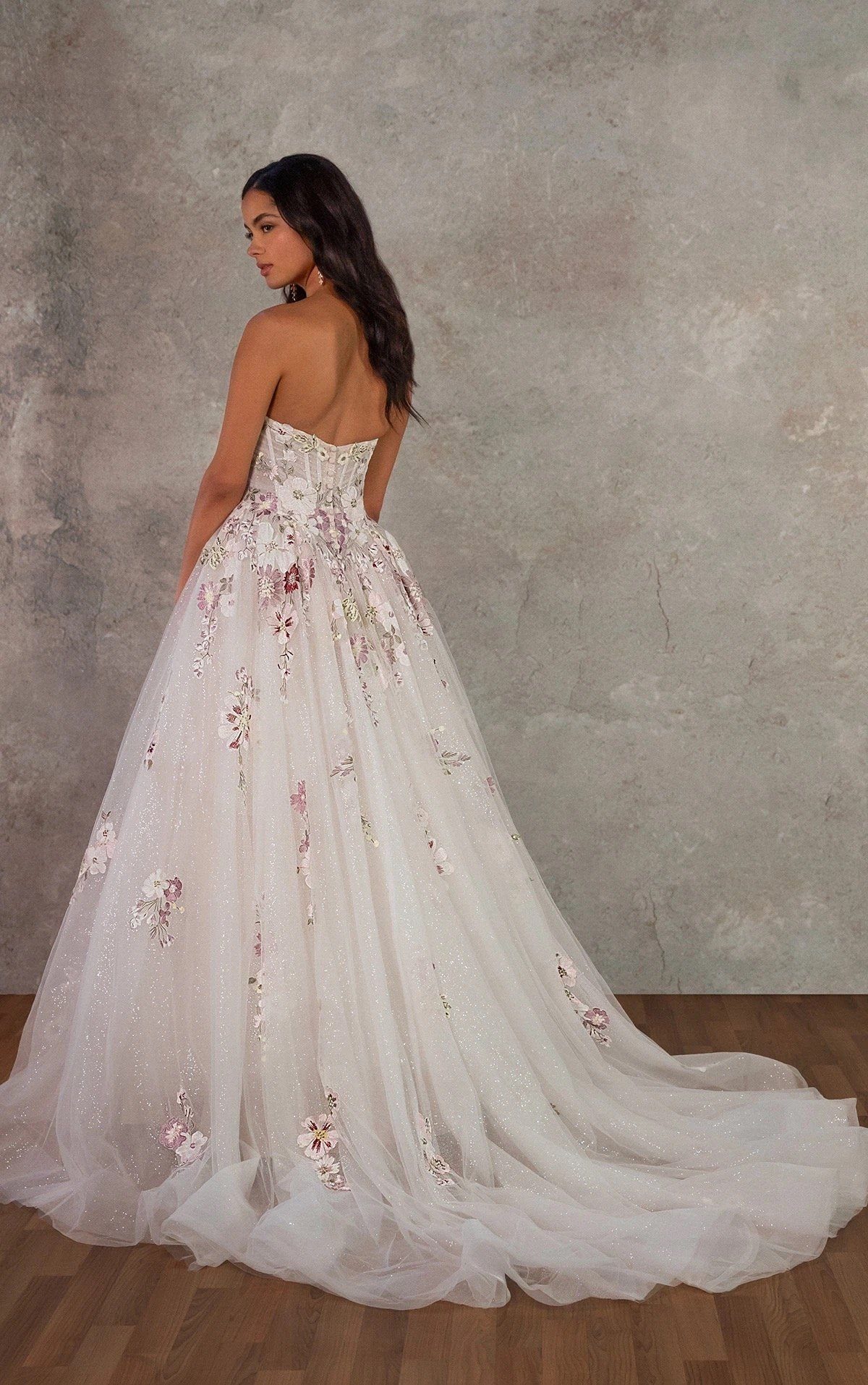 Woman in a white strapless wedding gown with pink and purple floral embroidery.