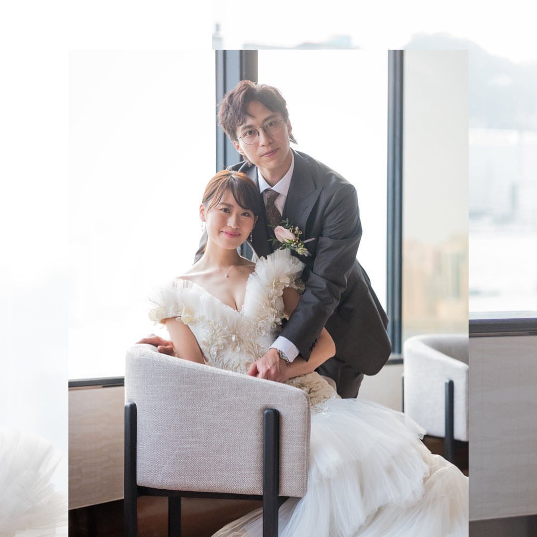 Bride in a white ruffled wedding gown and groom in a dark suit posing.