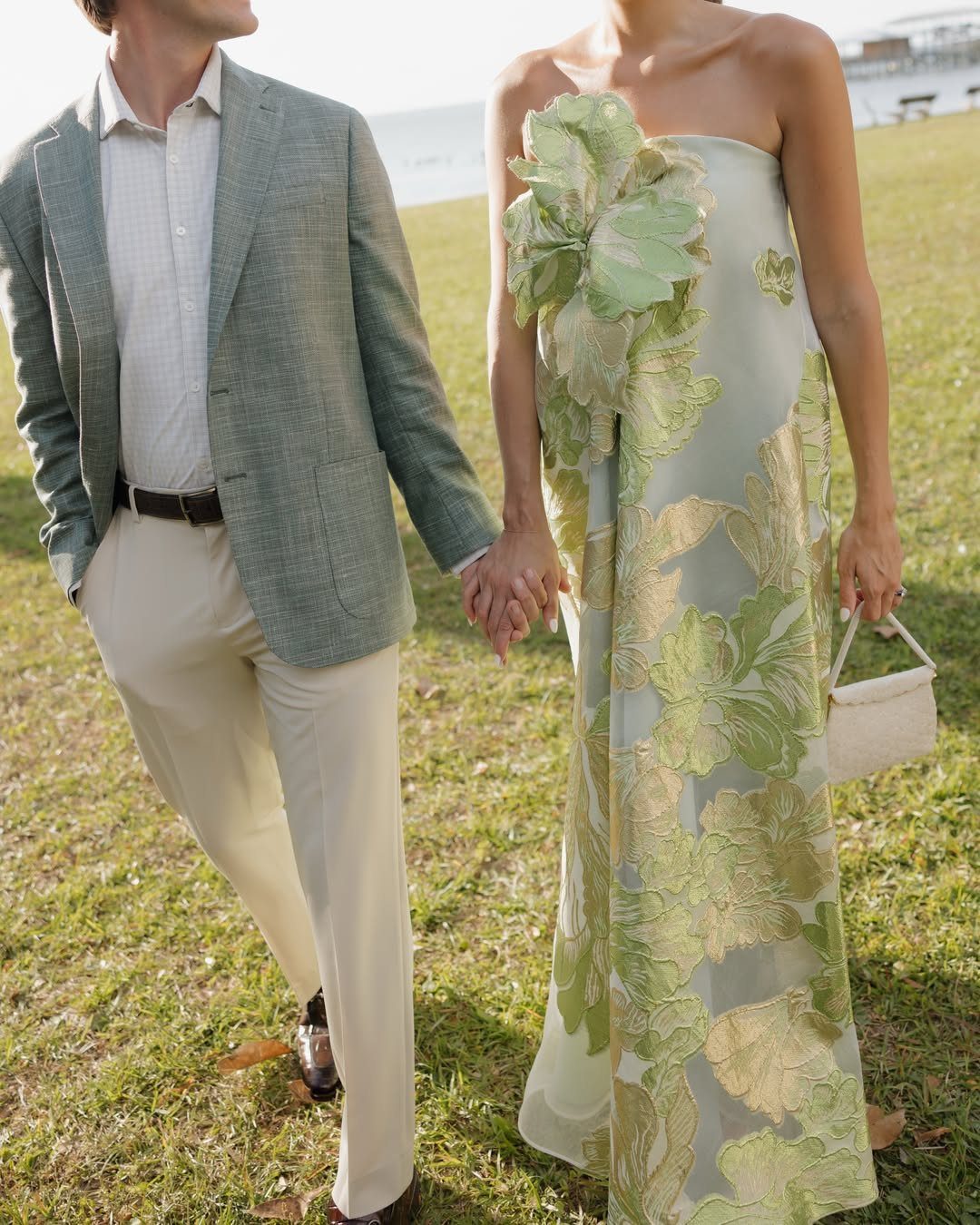Couple in semi-formal beach attire, man in green blazer and woman in floral maxi dress.