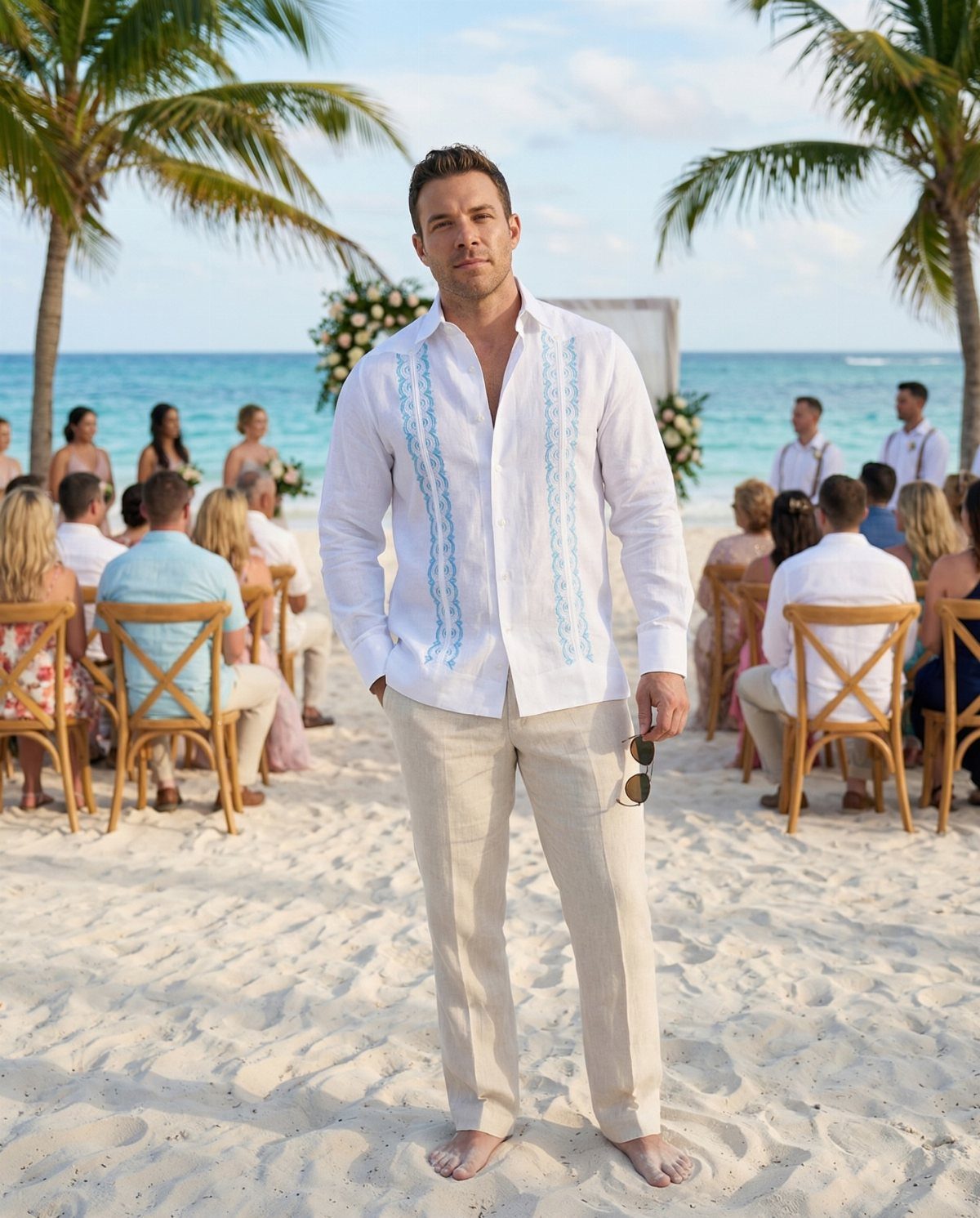 Man in white embroidered guayabera and beige linen pants at a beach wedding.
