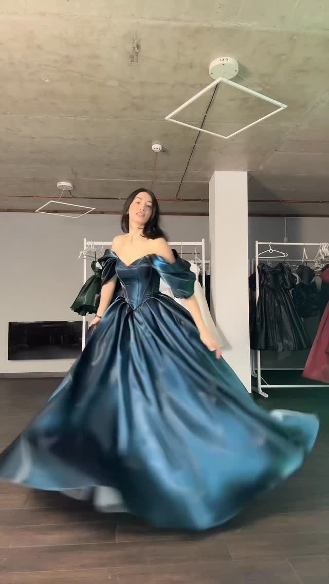 Woman wearing a voluminous off-the-shoulder teal blue satin maxi dress in a studio