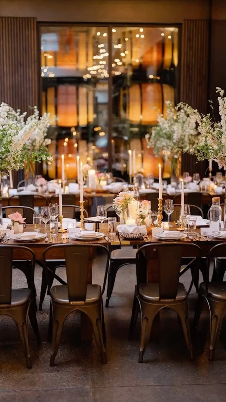 Wedding reception table with white flowers and candles in front of wine barrels.