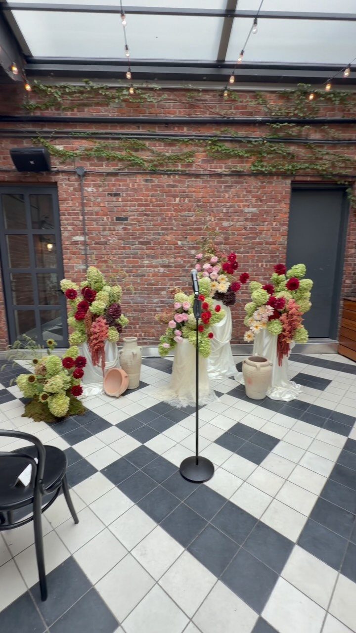 Floral arrangements against a red brick wall on a black and white checkered floor
