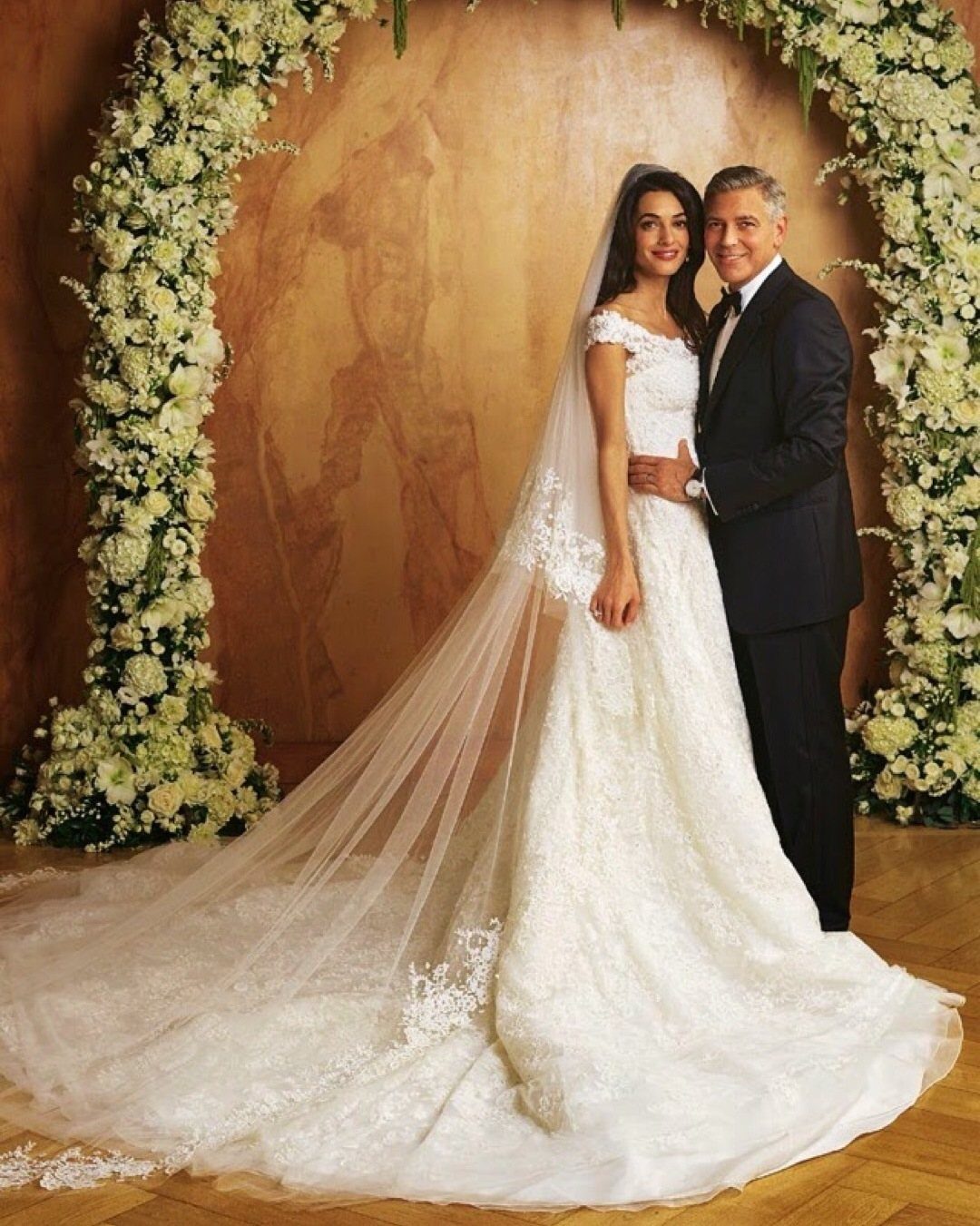 Amal Clooney in a white lace wedding dress and George Clooney in a tuxedo.