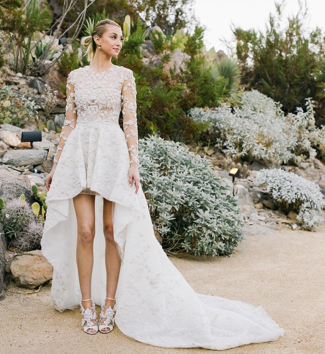 Woman in a white lace high-low wedding gown standing in a succulent garden.