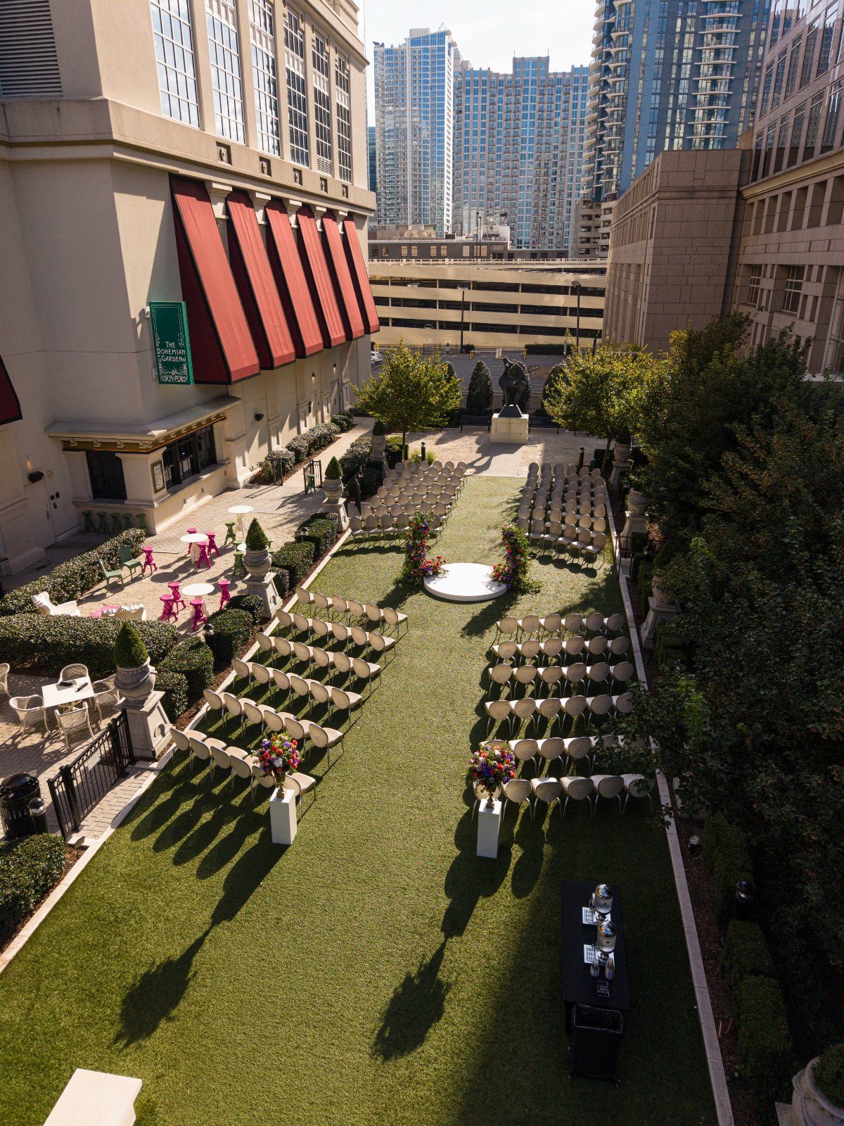 Rooftop wedding ceremony setup with white chairs and floral arrangements amidst city skyscrapers.