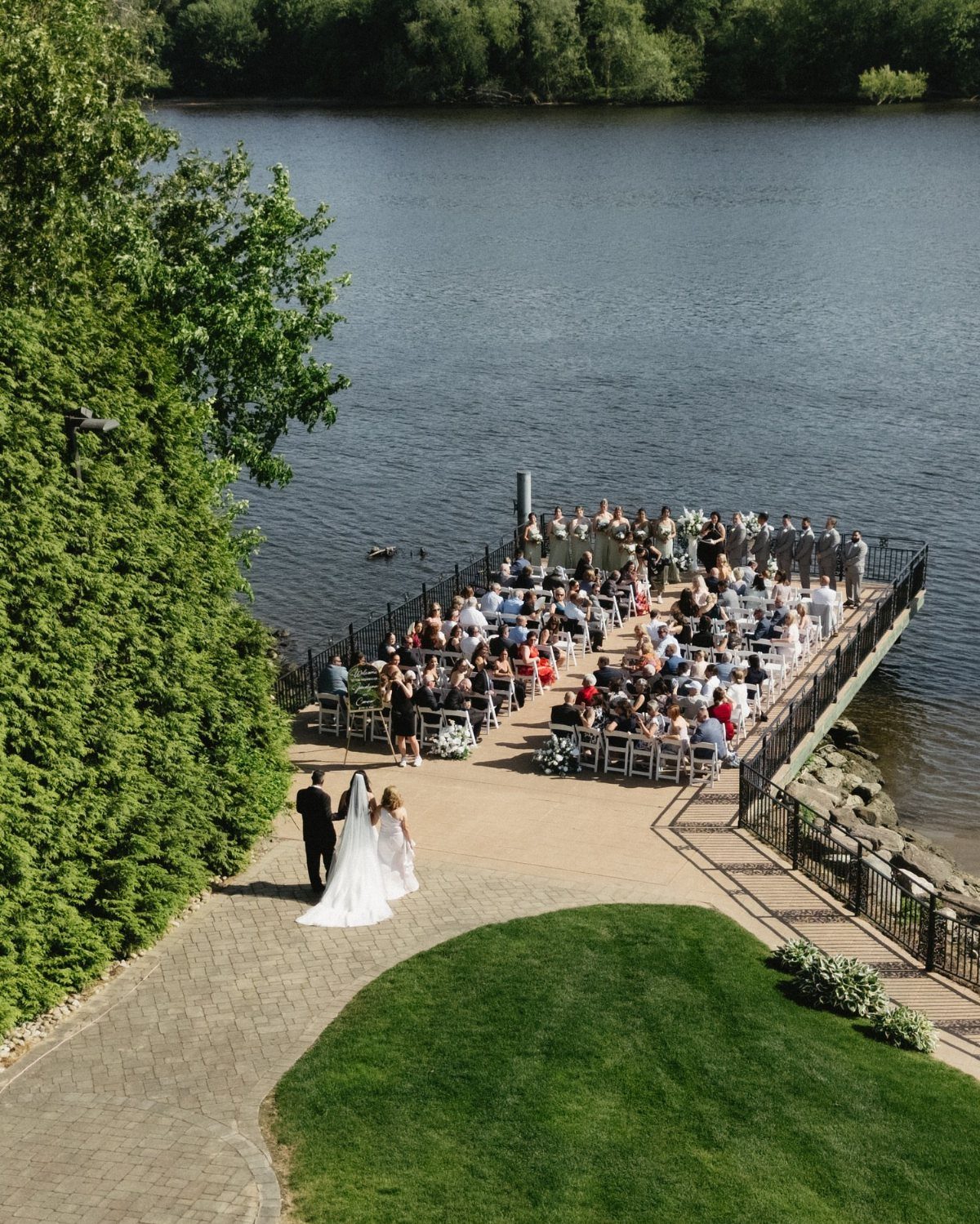 Bride and groom walking toward guests for a wedding ceremony on a lakeside pier