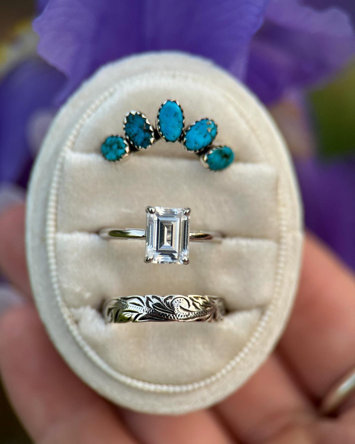 Three rings in a white box, including one with turquoise stones and a diamond.