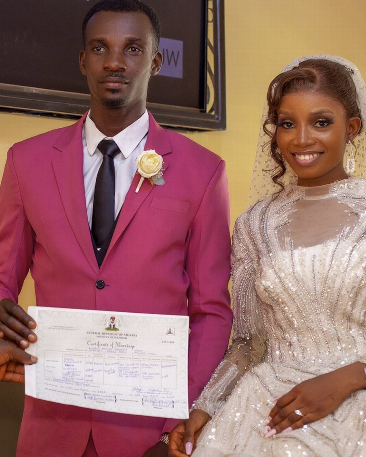 Couple in wedding attire holding a marriage certificate after their ceremony.