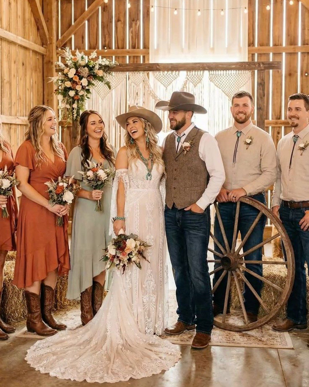 Wedding party in a rustic barn wearing western attire and cowboy boots.