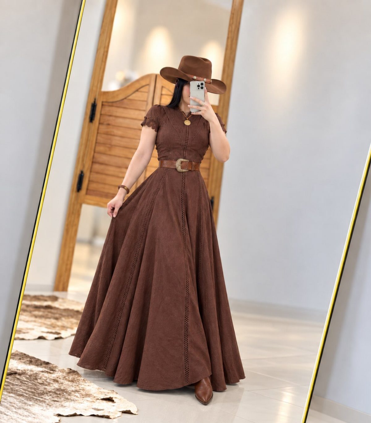 Woman wearing a brown fit-and-flare maxi dress, cowboy hat, and brown leather boots.