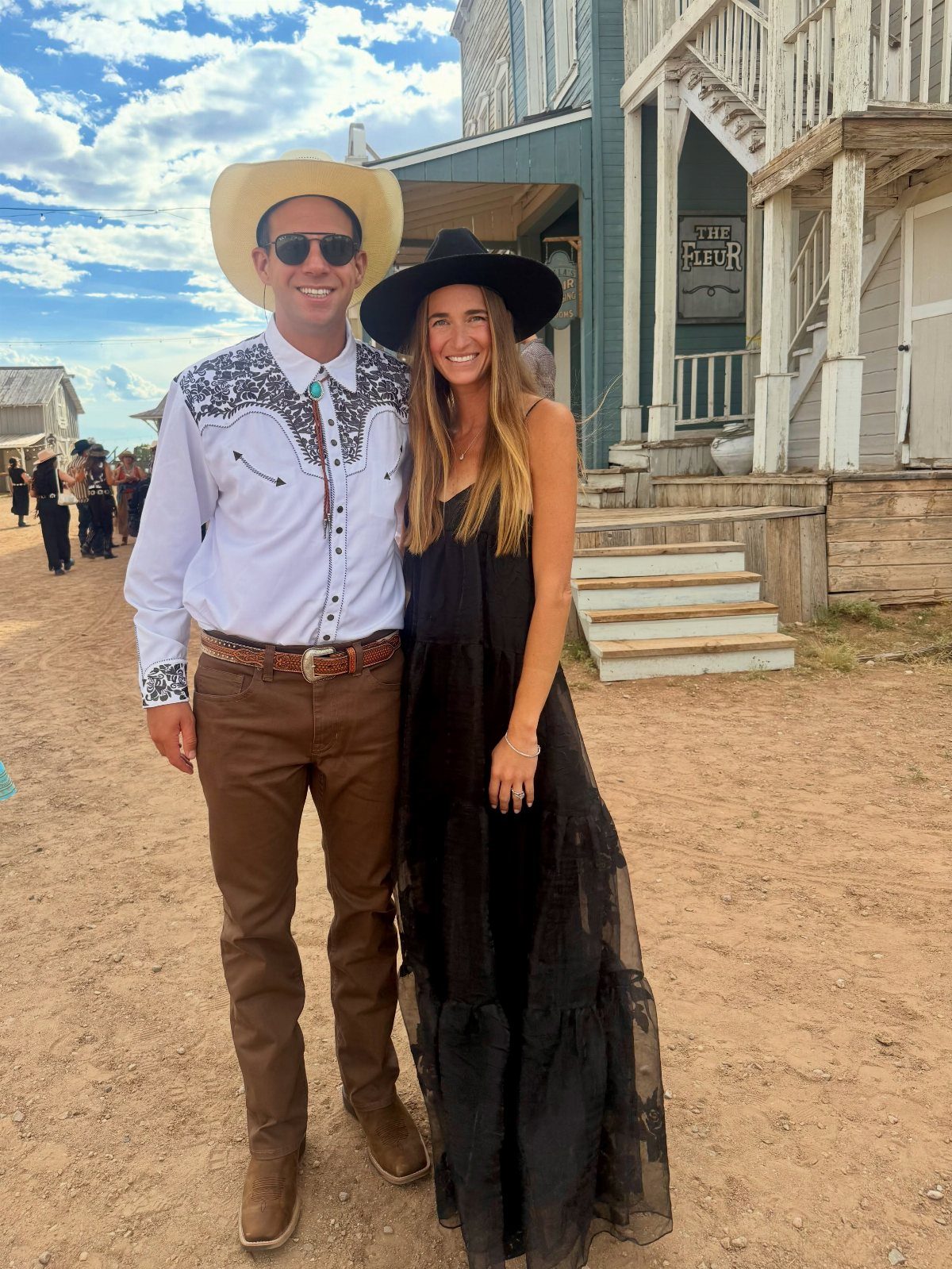 Man in western shirt and woman in black dress wearing cowboy hats.
