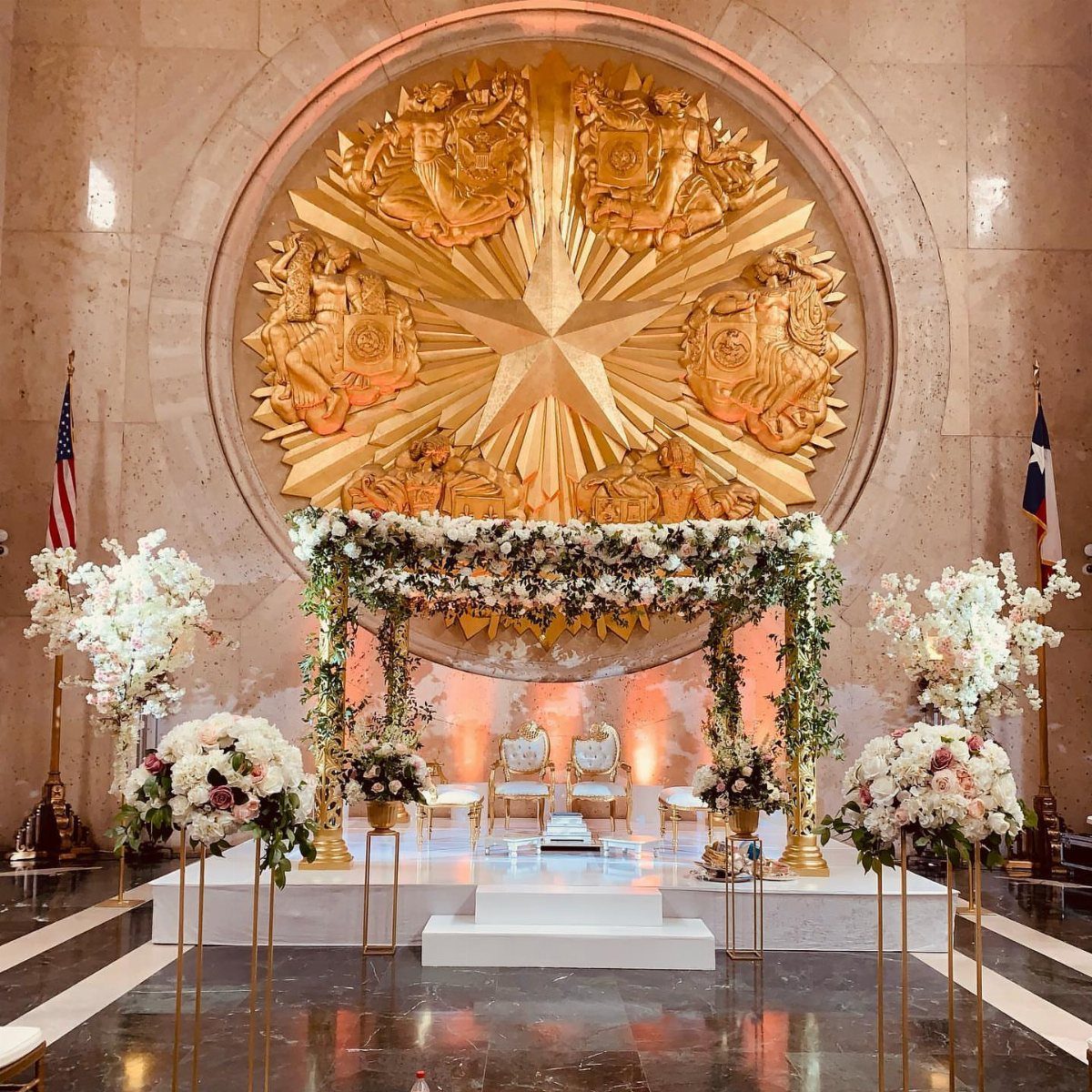 Wedding ceremony setup with white flowers and a large golden star wall sculpture.