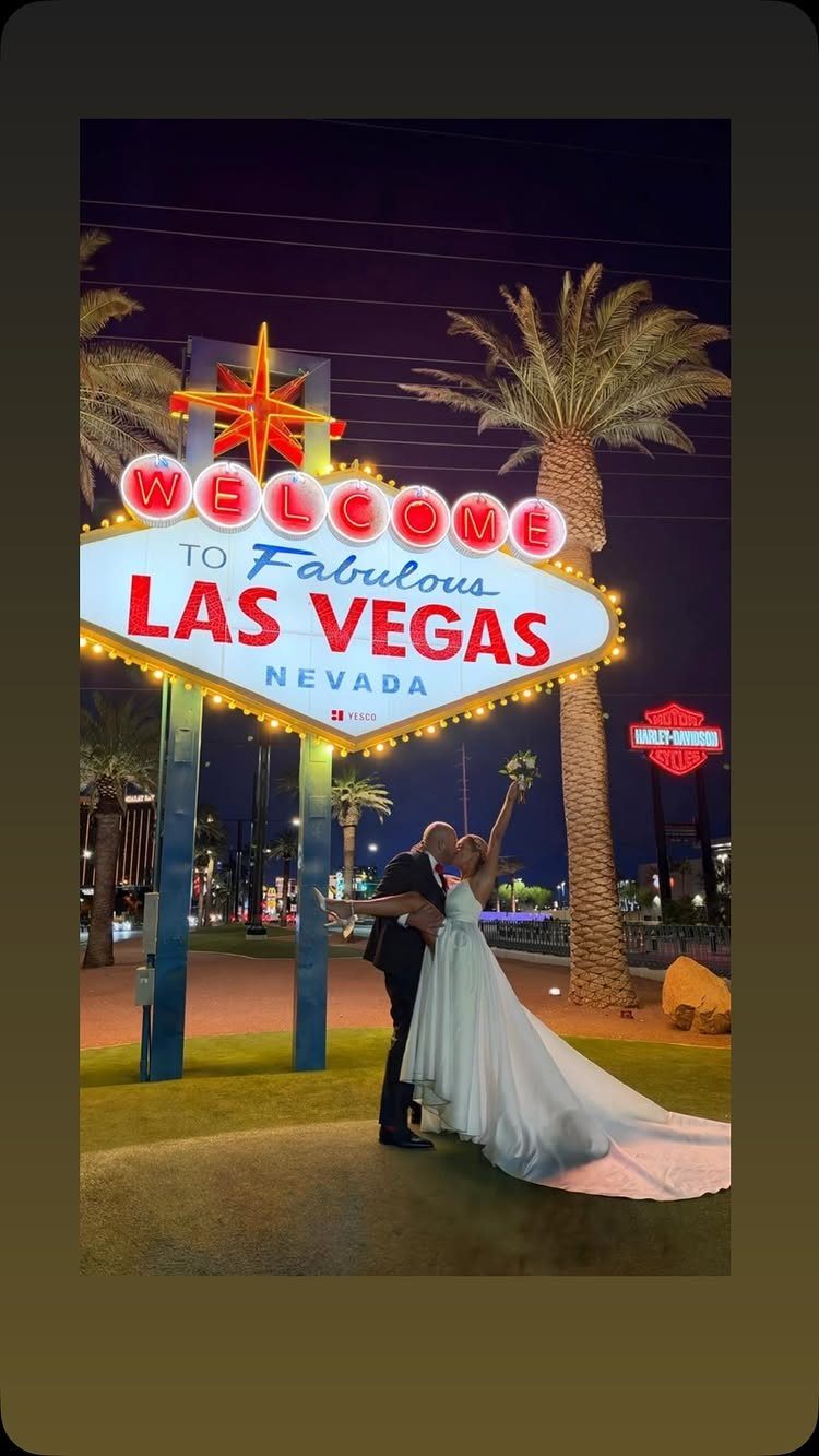 Newlywed couple kissing in front of the Welcome to Fabulous Las Vegas sign at night.