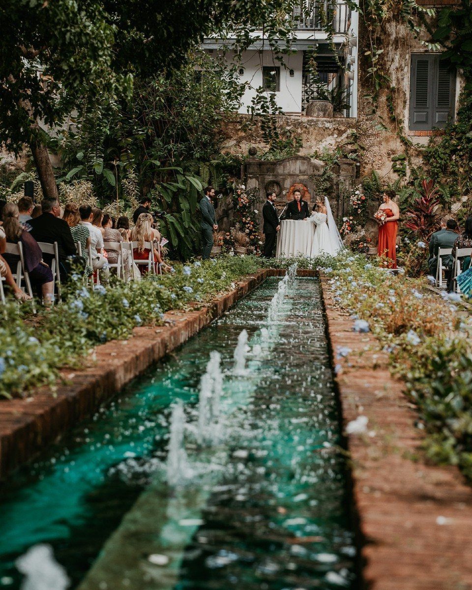 Wedding ceremony in a lush garden with a long turquoise fountain feature.