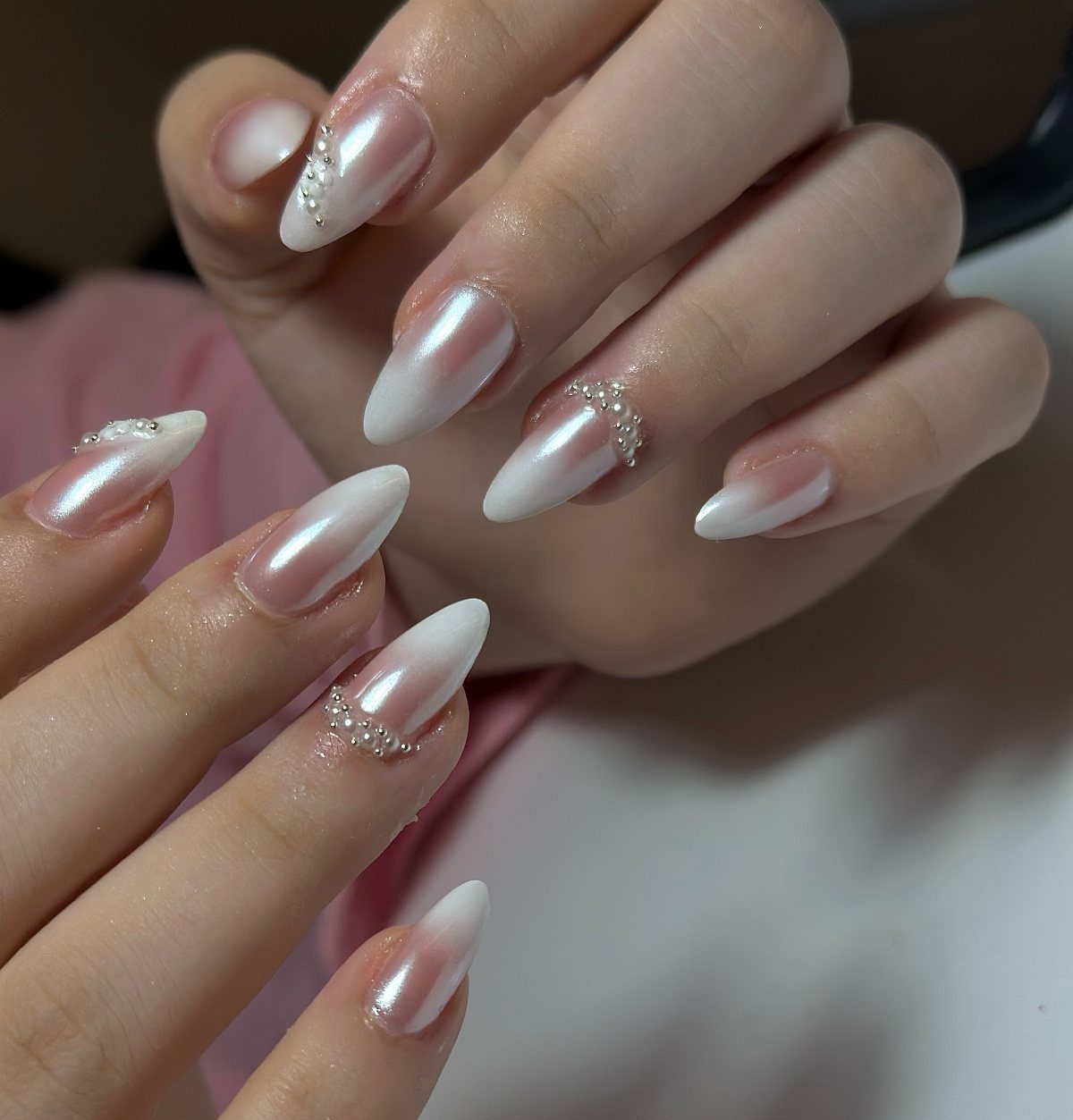 Almond-shaped nails with white and pink ombre gradient and pearlescent chrome finish.