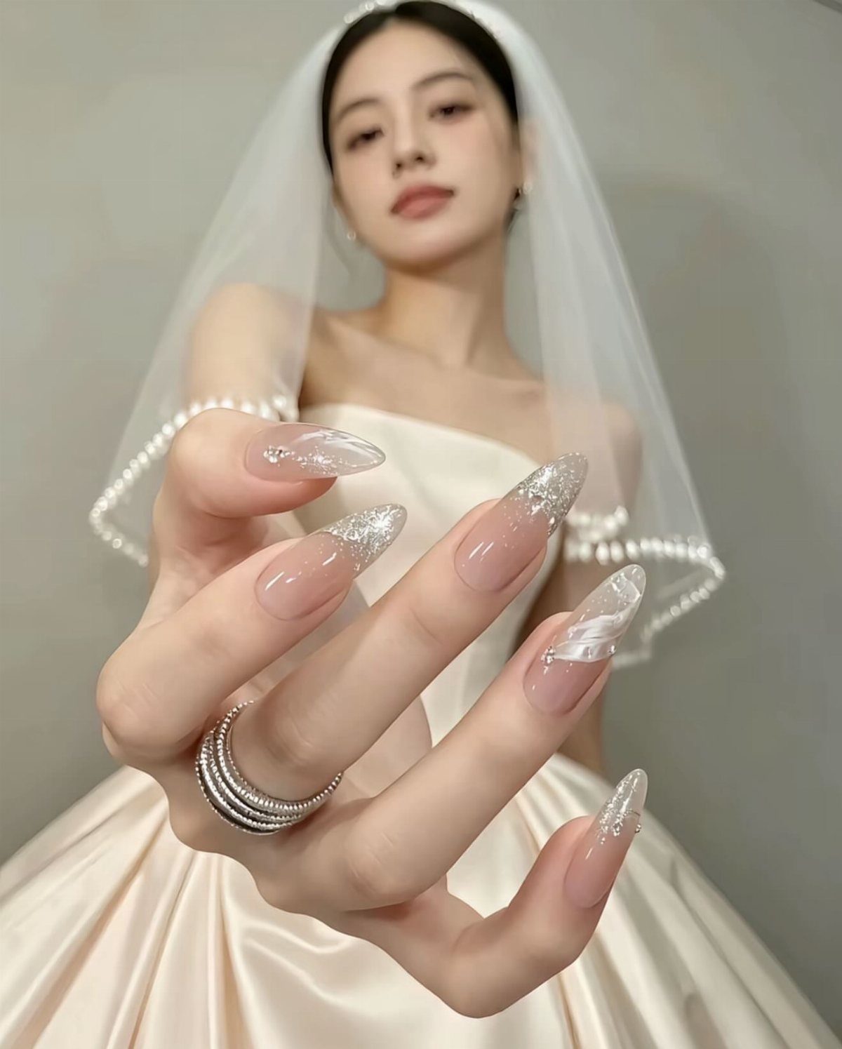 Almond shaped nude nails with silver glitter tips on a bride's hand