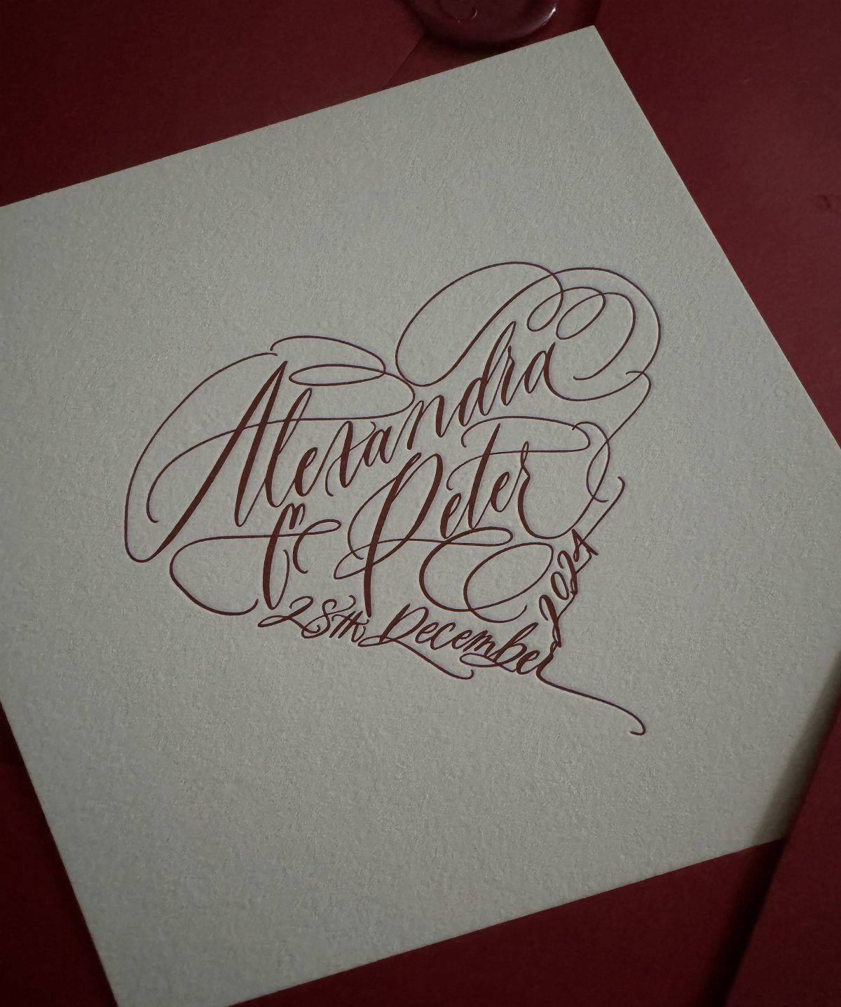 Red calligraphic heart with names Alexandra and Peter on a white card.