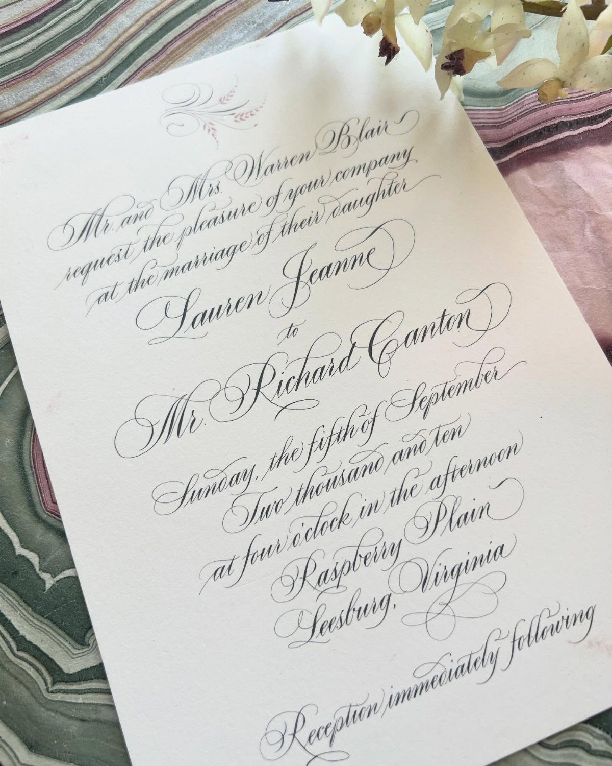 Wedding invitation with elegant black calligraphy script on white paper with floral accents