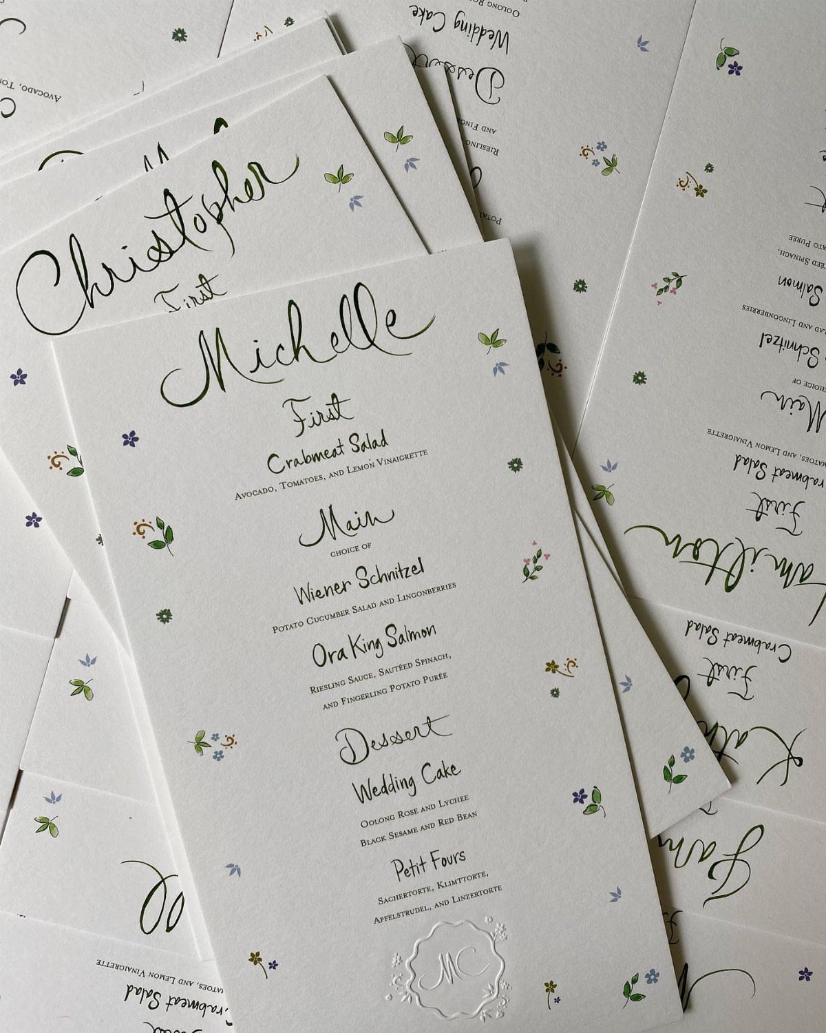 Wedding menu cards with elegant black calligraphy and small floral accents on white paper.