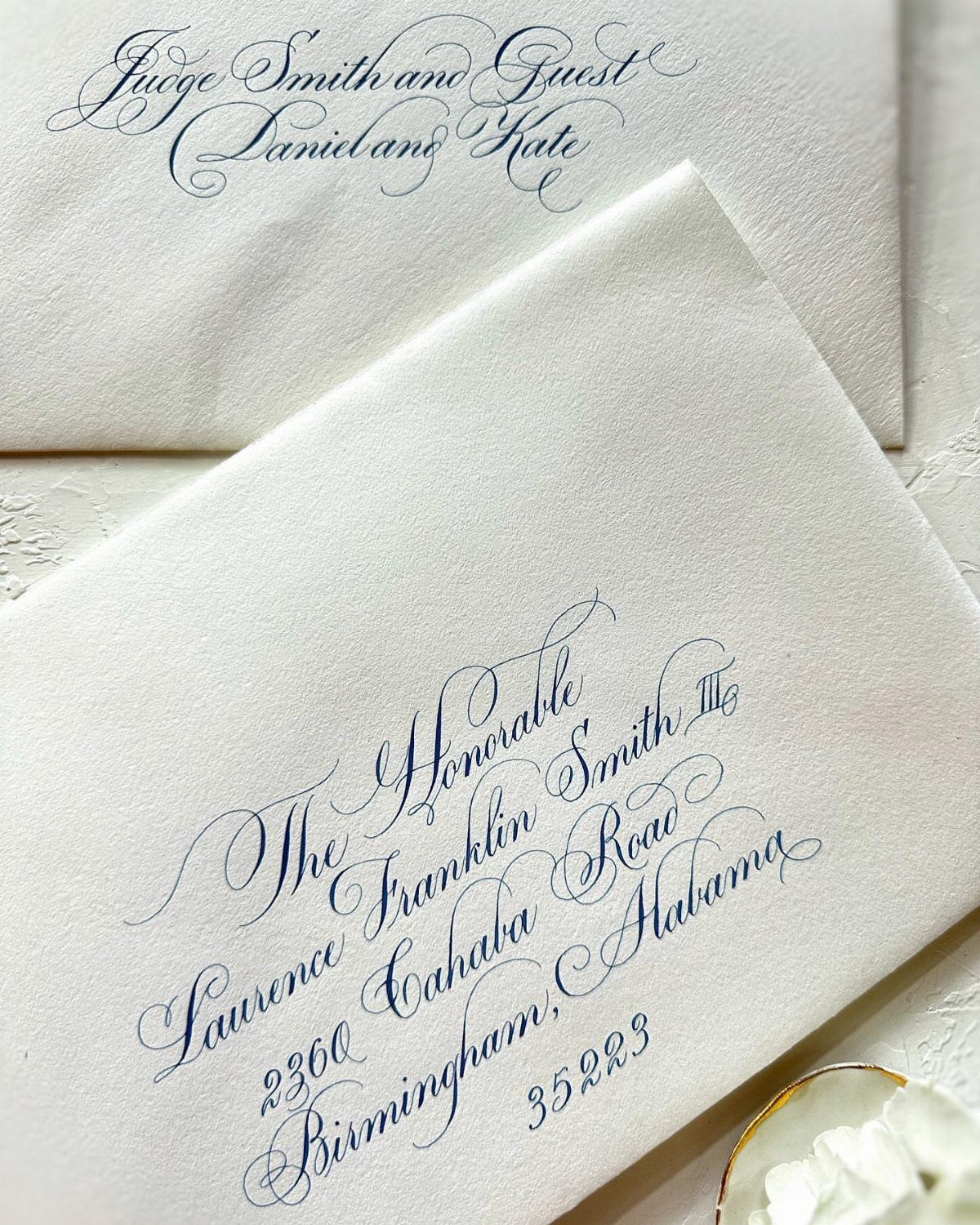White envelopes featuring elegant navy blue cursive calligraphy for a wedding invitation address.