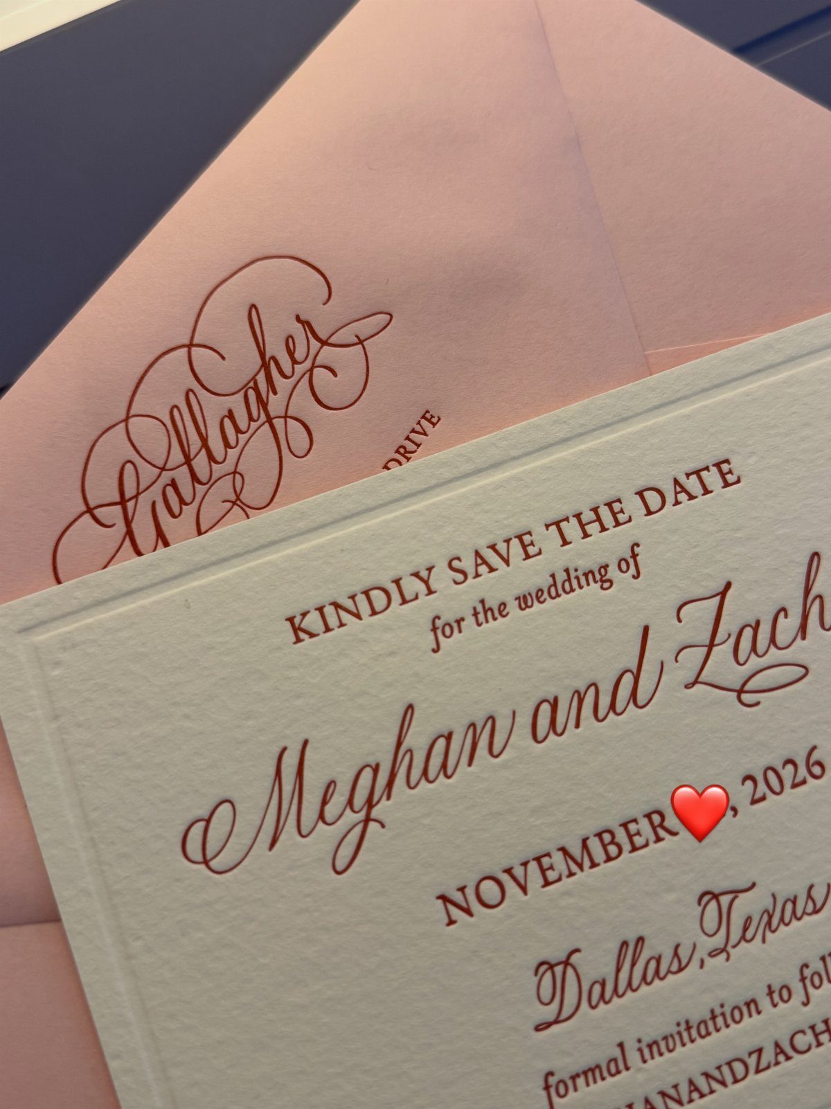 Wedding save the date card with red elegant script and serif typography on white paper.