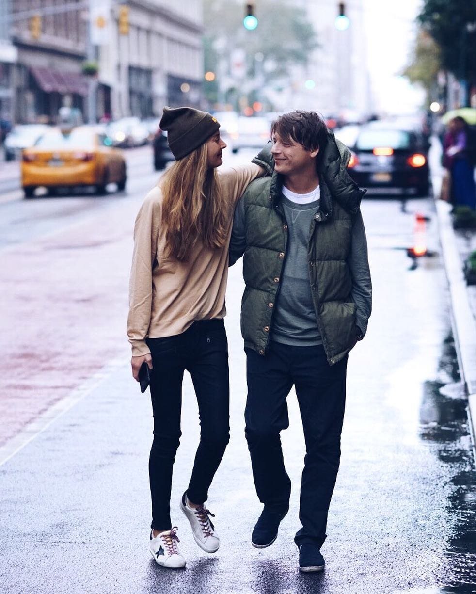 Couple walking on a wet city street wearing casual autumn clothing and sneakers.