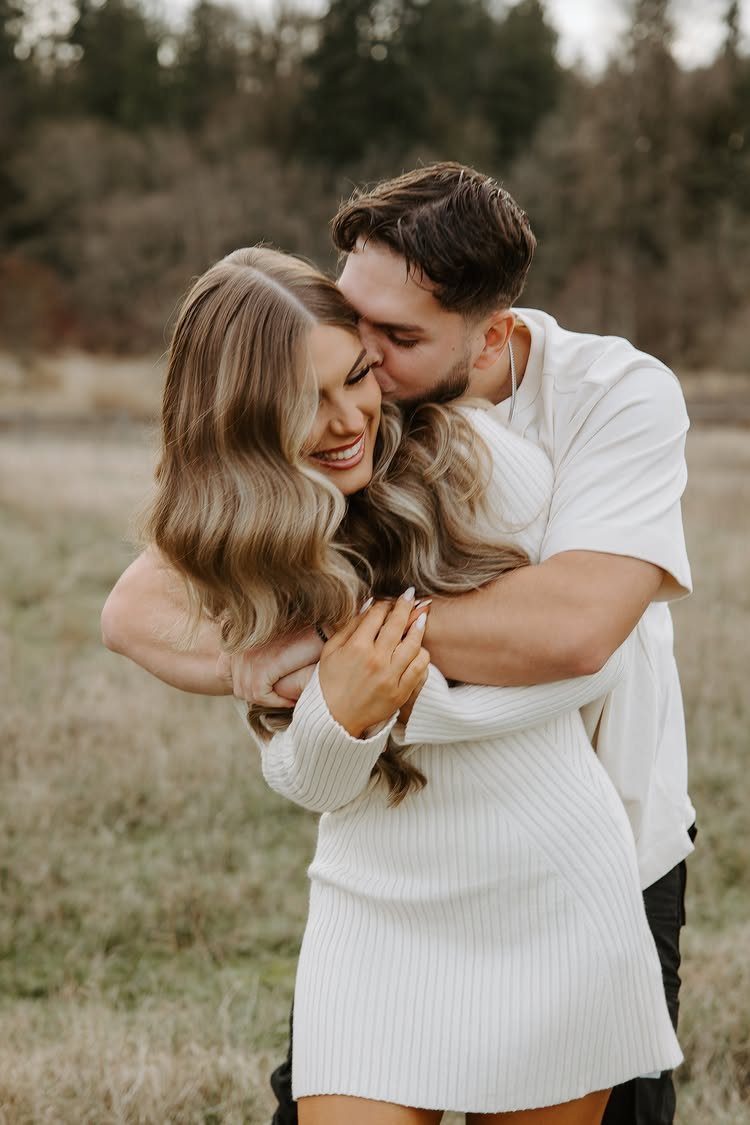 Couple embracing in a field, woman wearing a white ribbed knit dress.