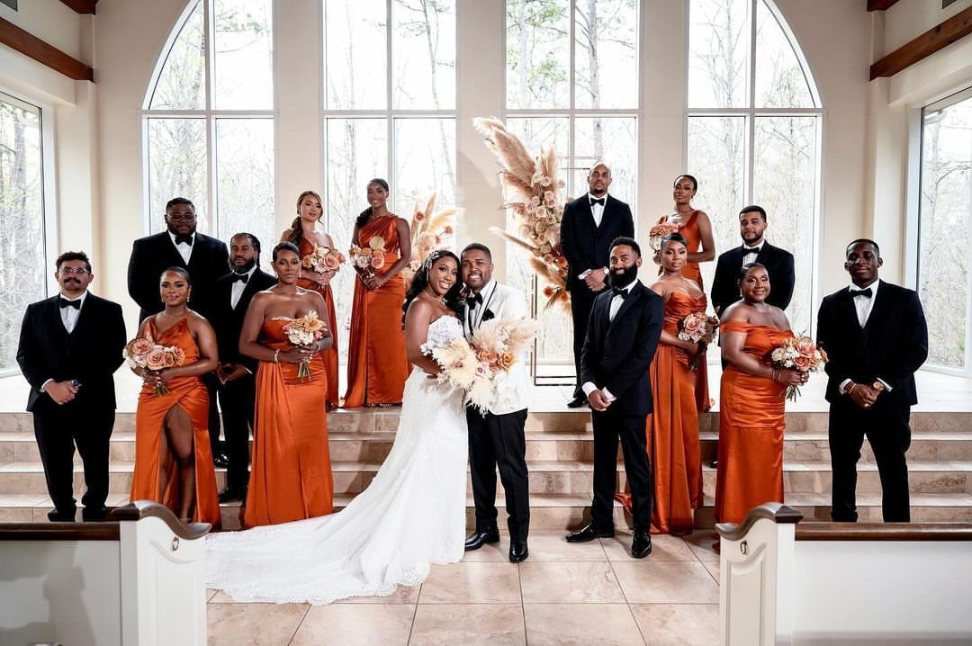 Wedding party with bridesmaids in burnt orange dresses and a bride in white.