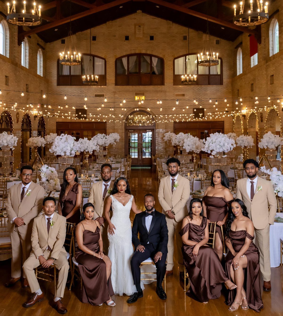 Wedding party in mocha brown and tan attire posing in a brick hall.