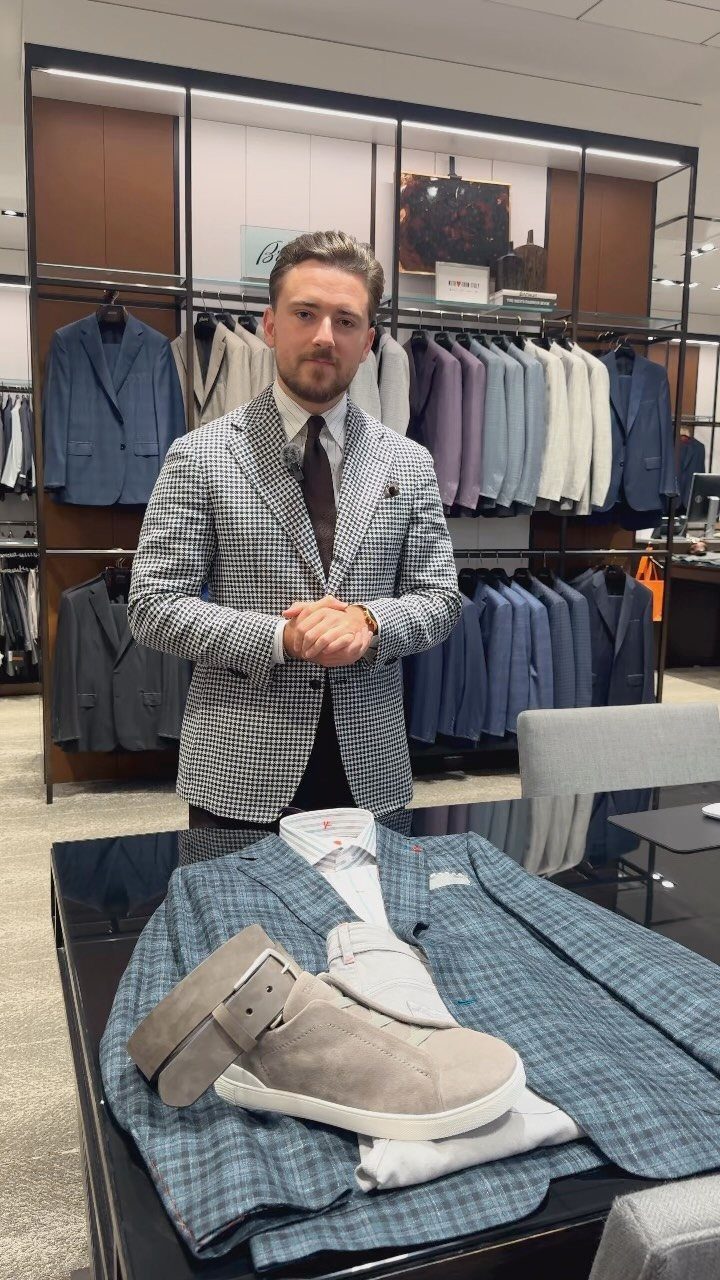 Man wearing a checkered blazer standing in a high-end men's clothing store.