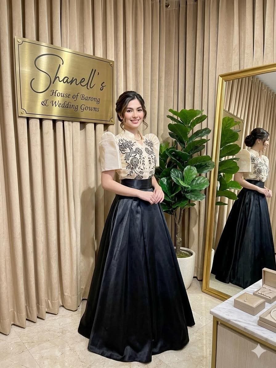 Woman wearing a cream butterfly-sleeved embroidered top and black satin wedding skirt