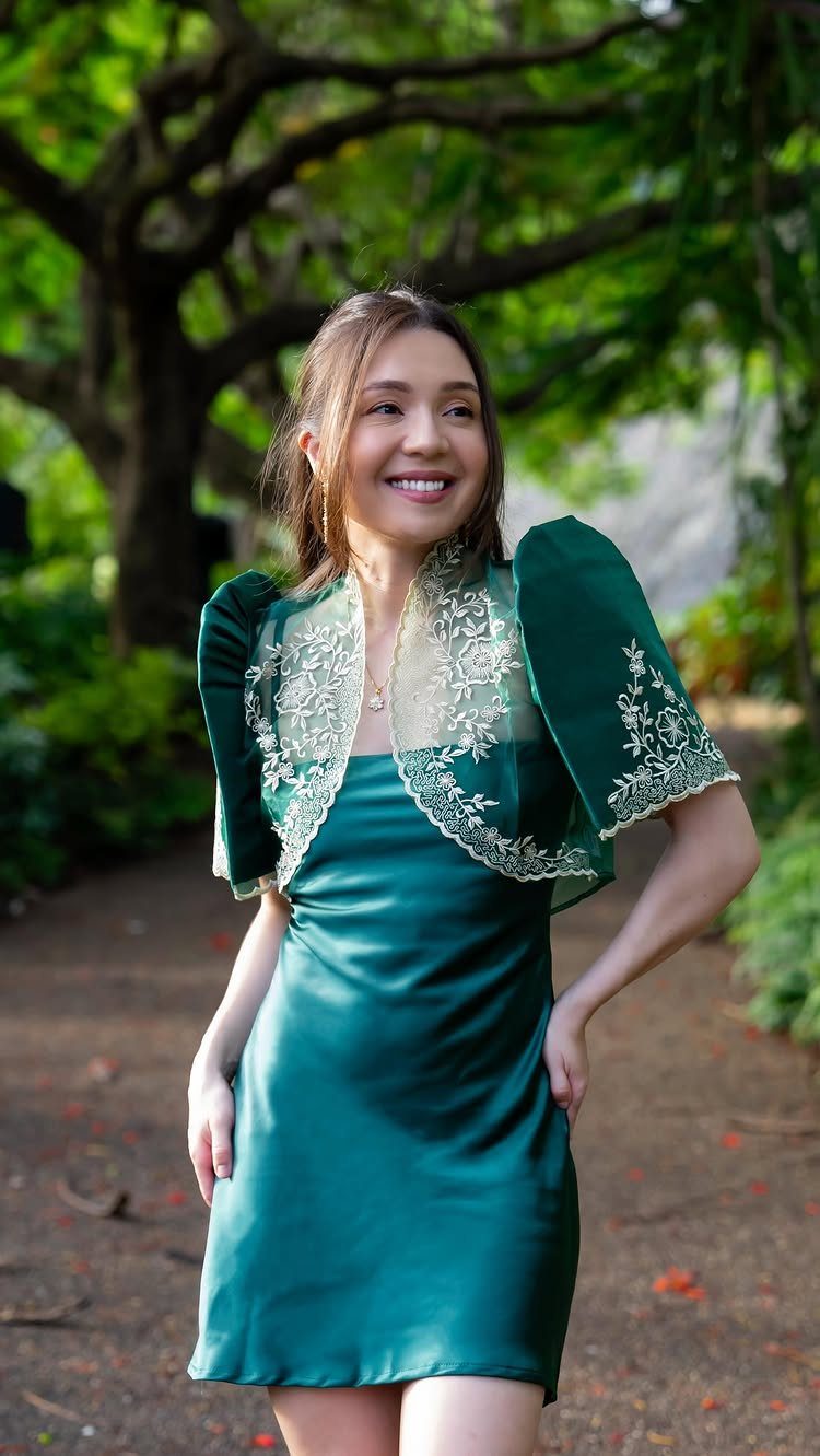 Woman in a green satin dress and embroidered butterfly sleeve bolero in a garden