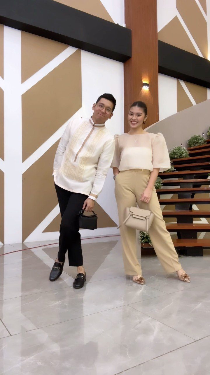 Man in Barong Tagalog and woman in cream blouse and tan trousers posing together.