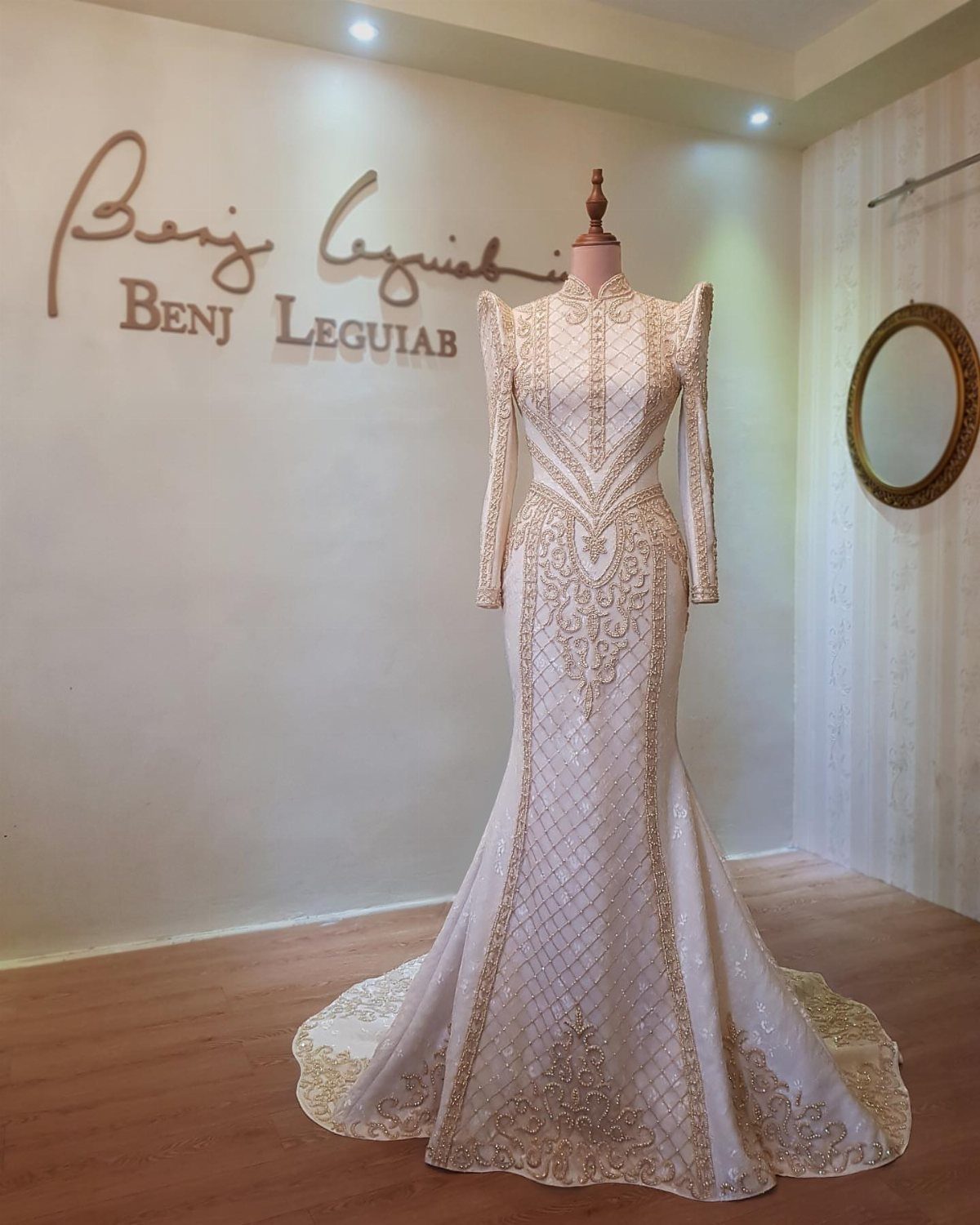 White mermaid gown with butterfly sleeves and gold embroidery on a mannequin.