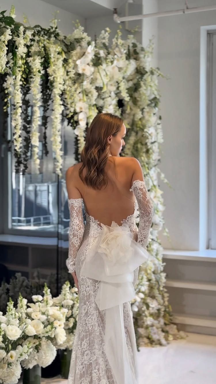 Woman in a white lace sheath wedding dress with a large back bow.