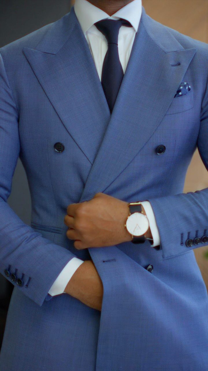 Person wearing a tailored double-breasted light blue suit with a dark blue tie.