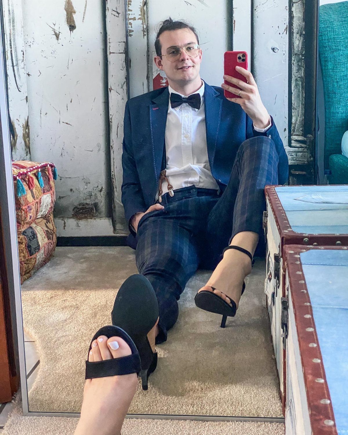Person in a navy suit and plaid trousers wearing black high-heeled sandals.