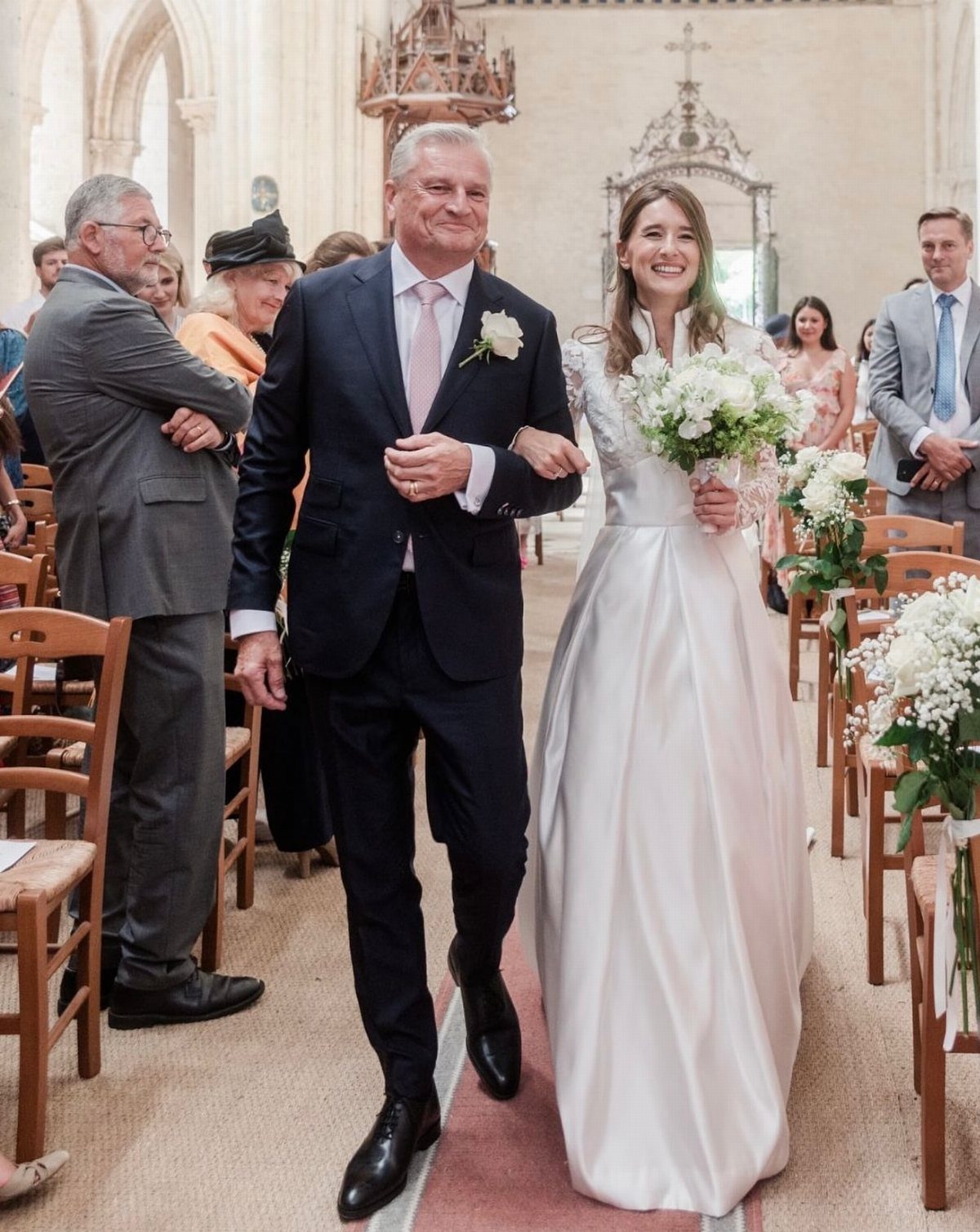 Father of the bride in a navy suit walking bride down church aisle