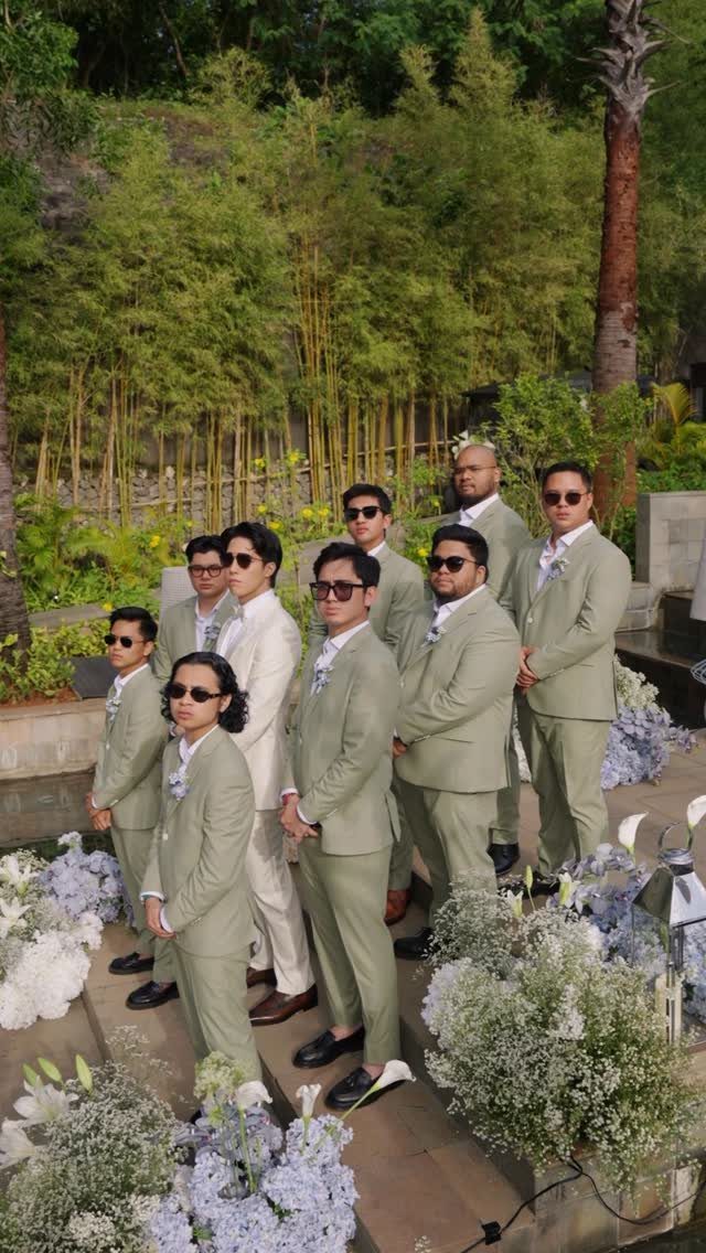 Group of men in matching tan suits and sunglasses at an outdoor wedding.