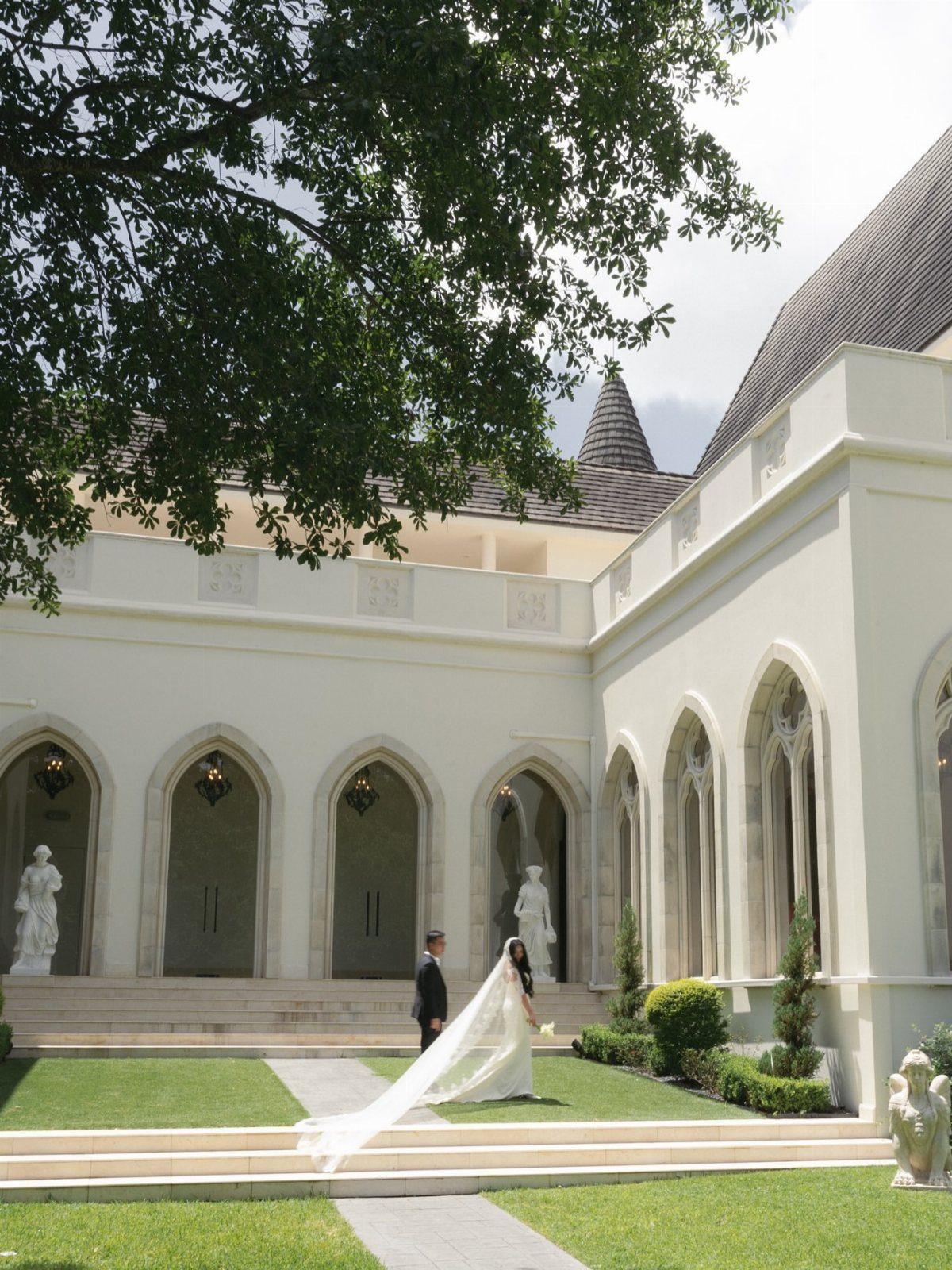 Bride and groom standing in the courtyard of a white French-inspired estate venue.