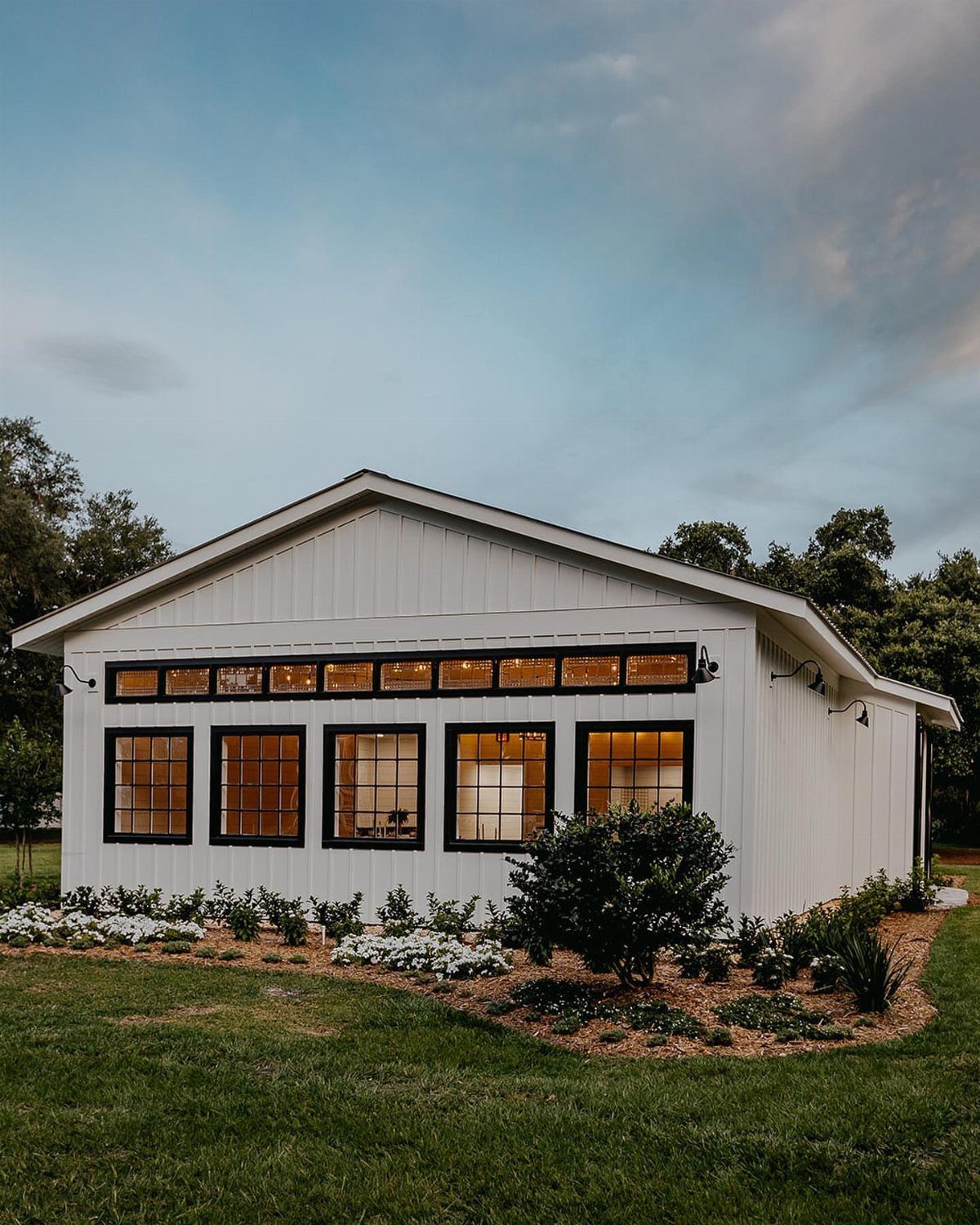 White wooden event venue with black windows in a grassy field.