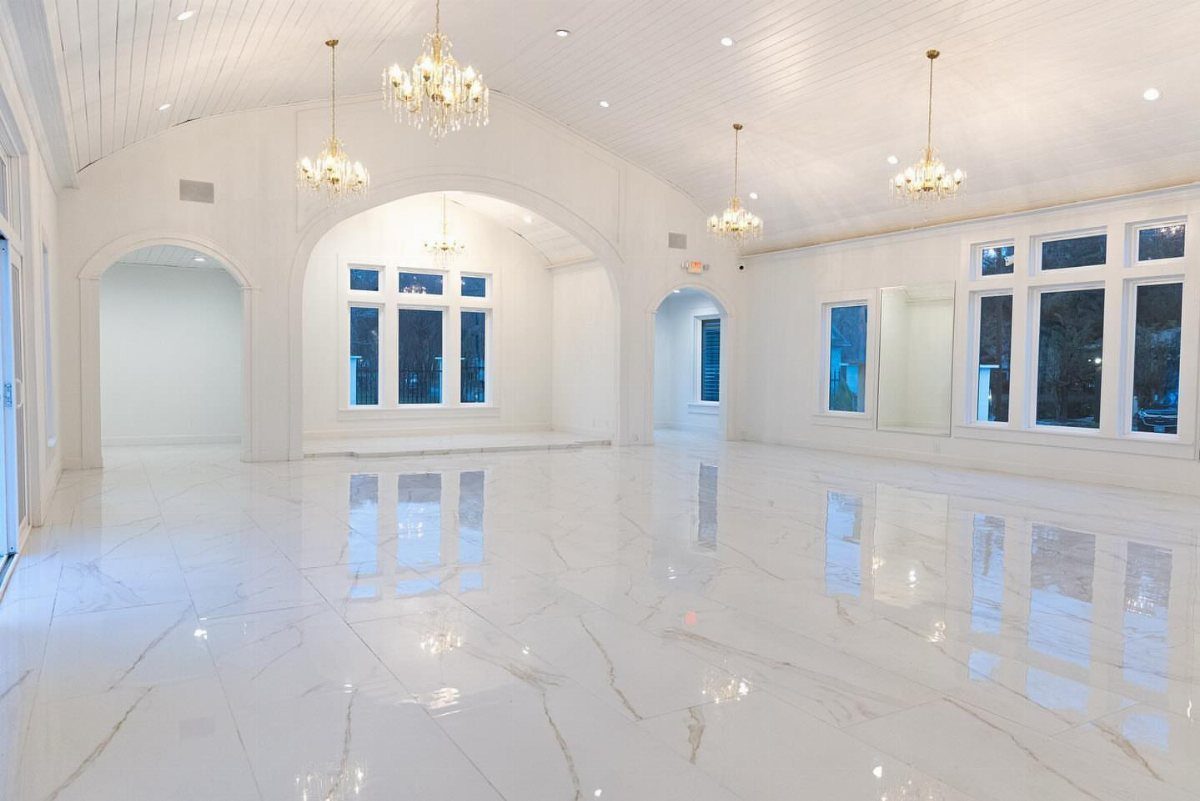 Empty white event venue with polished marble floors and gold crystal chandeliers.