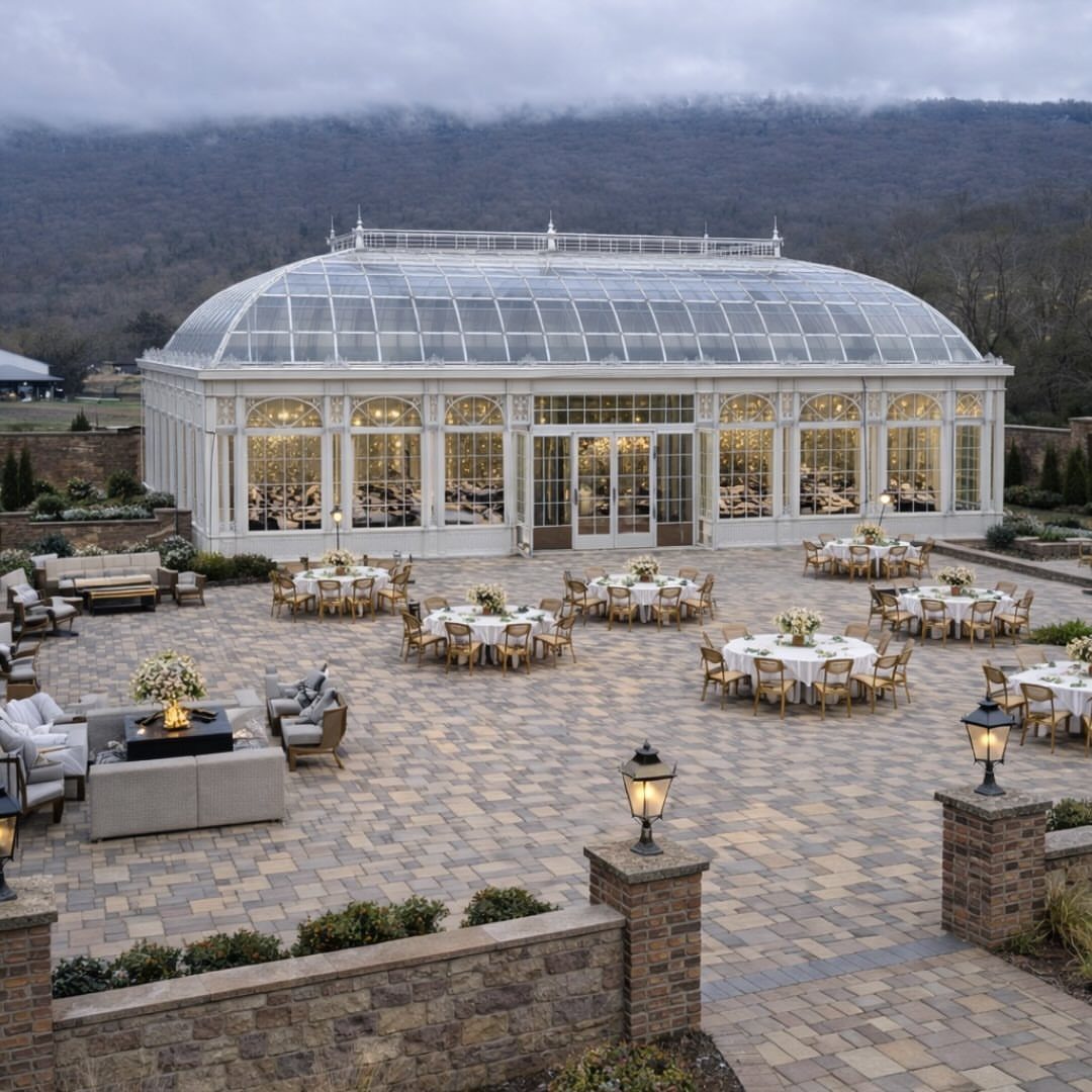 White glass conservatory building with an outdoor stone patio set for a wedding reception.