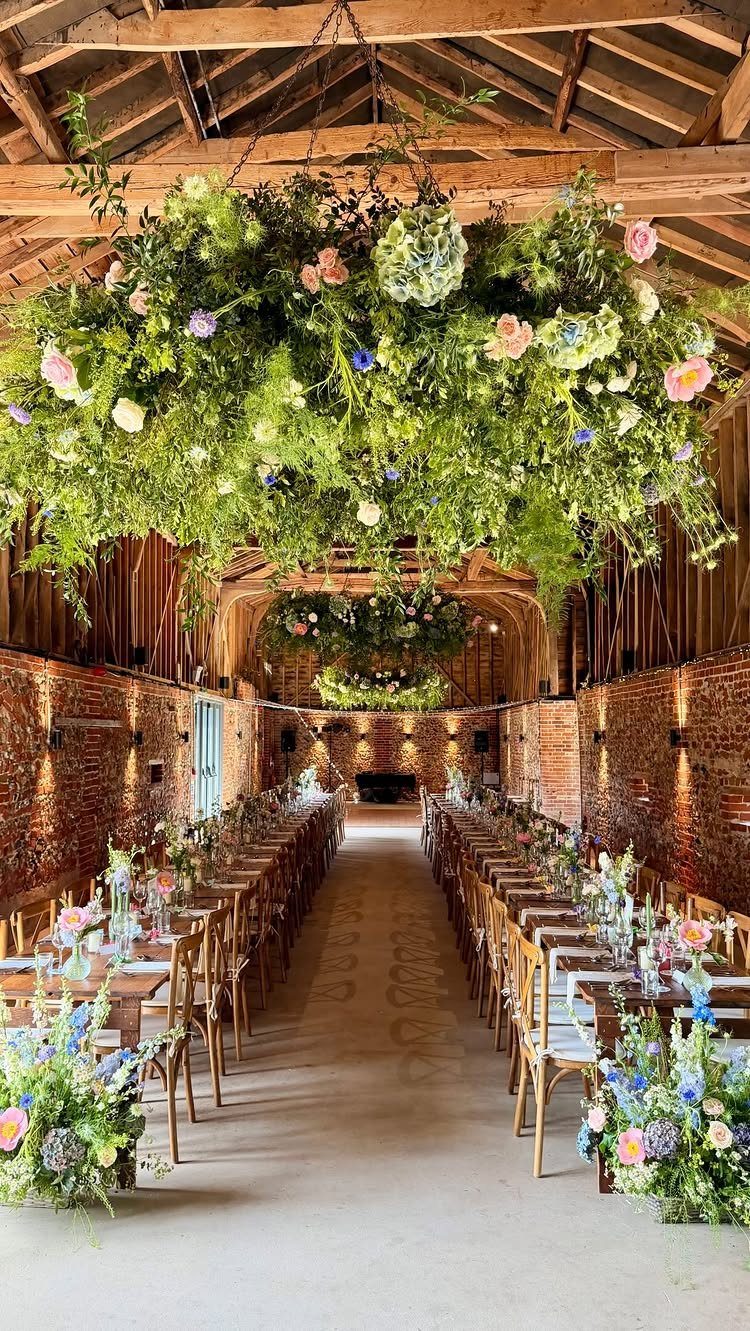 Rustic barn wedding venue with long wooden tables and hanging floral installations.